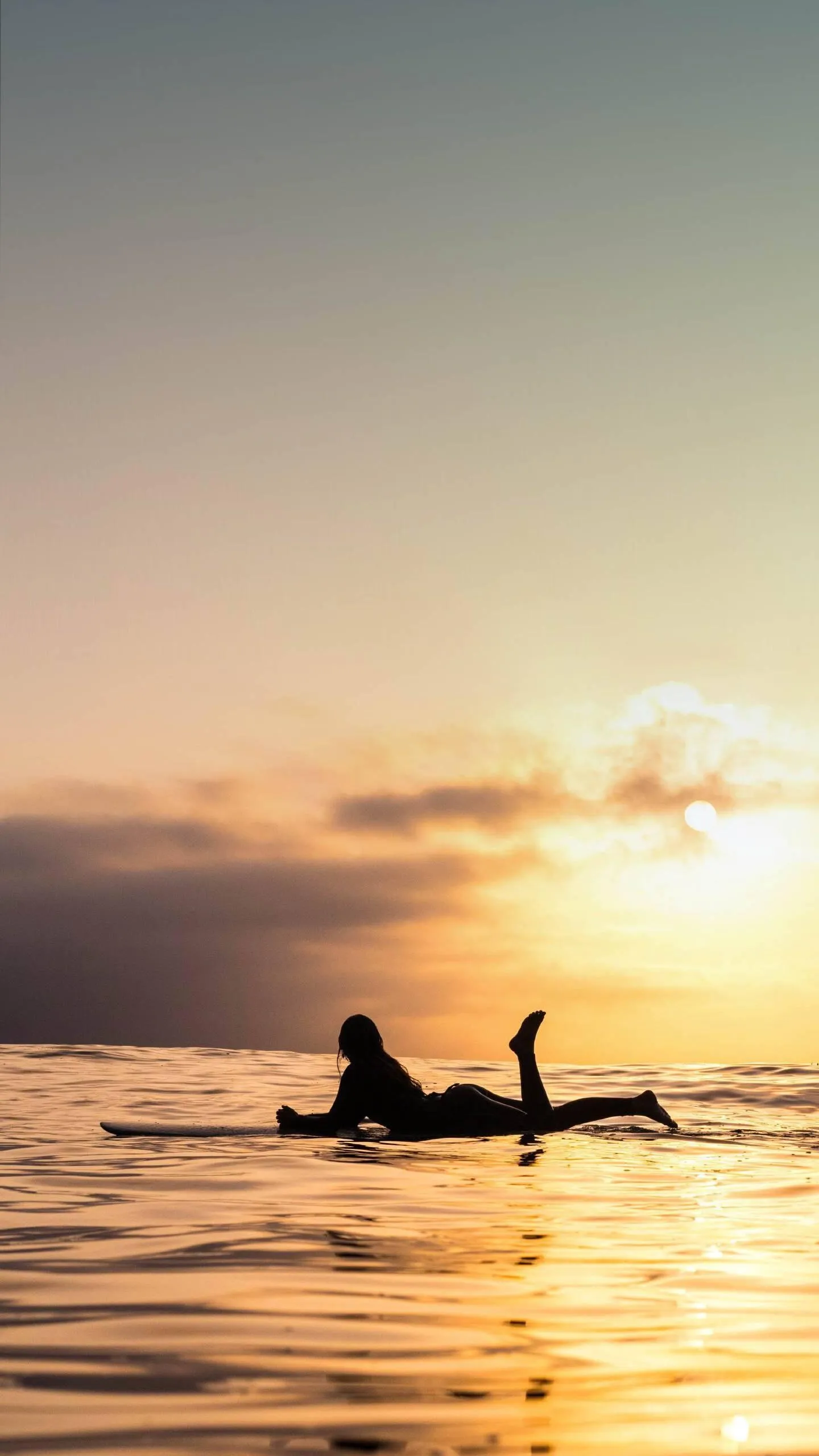 Sunset Silhouette of a Surfer in the Ocean with Gentle Waves