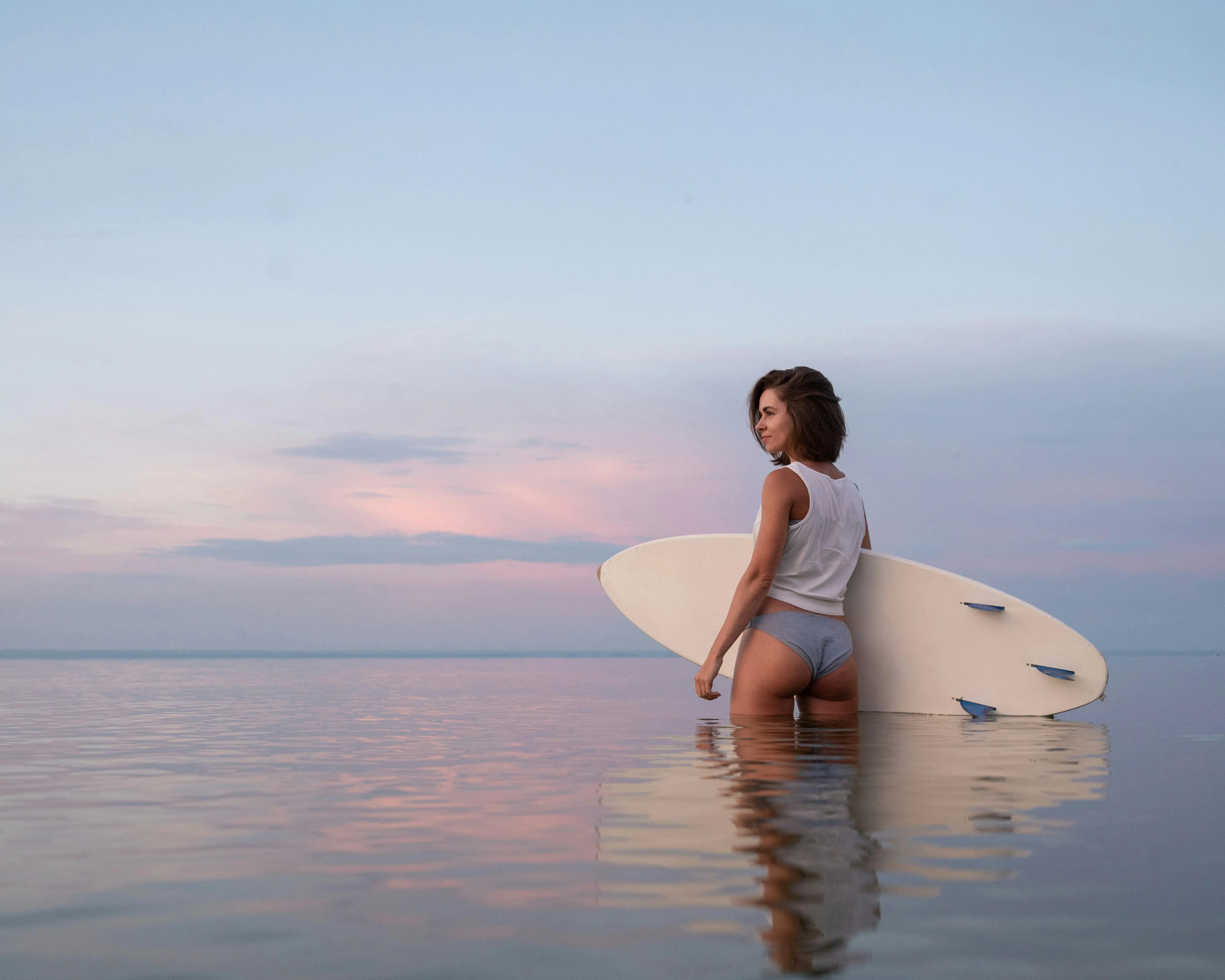 Surfer Girl Holding Board on the Ocean During Sunset Image