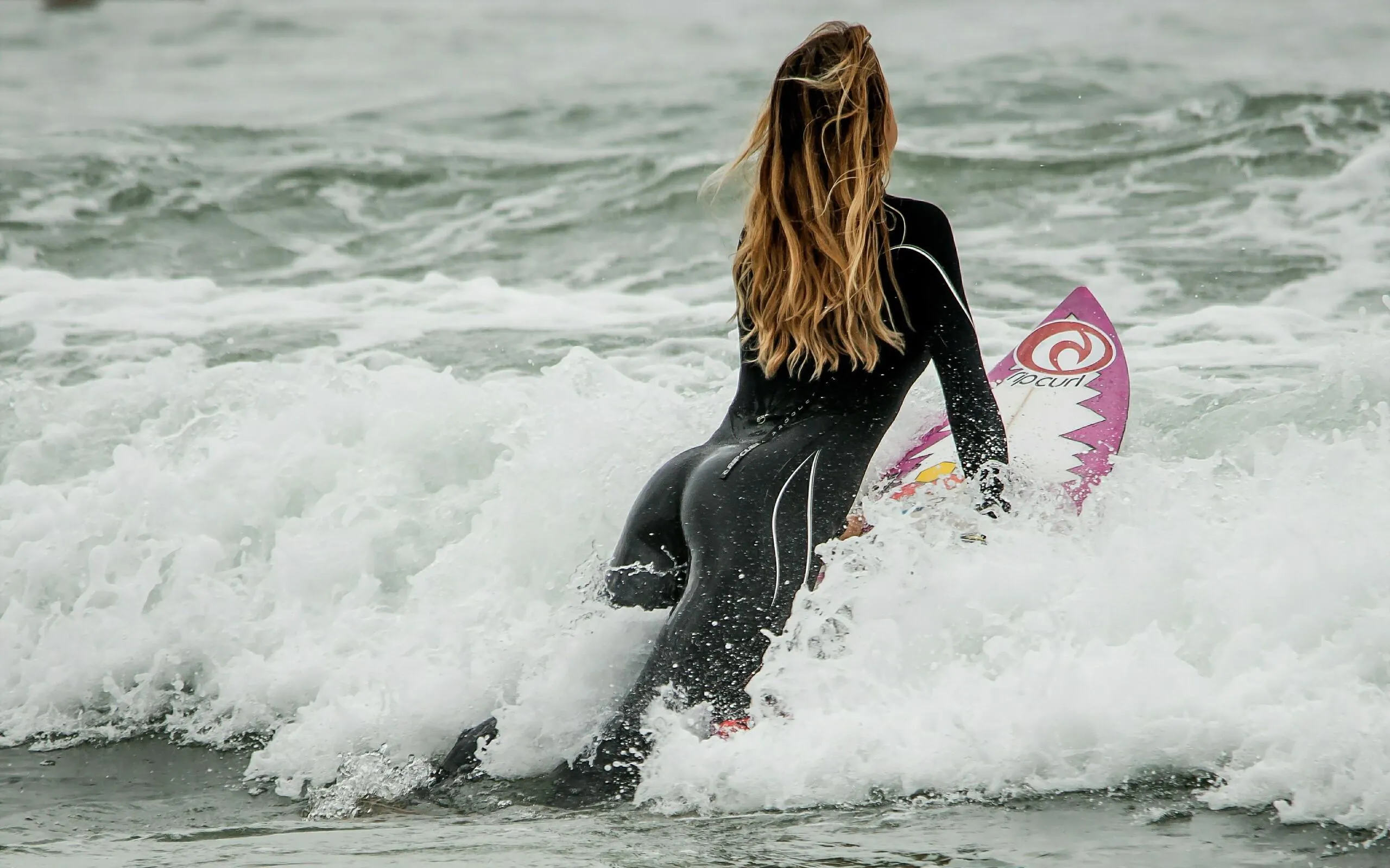 Surfer Girl Surfing Into the Ocean with a Pink Surfboard