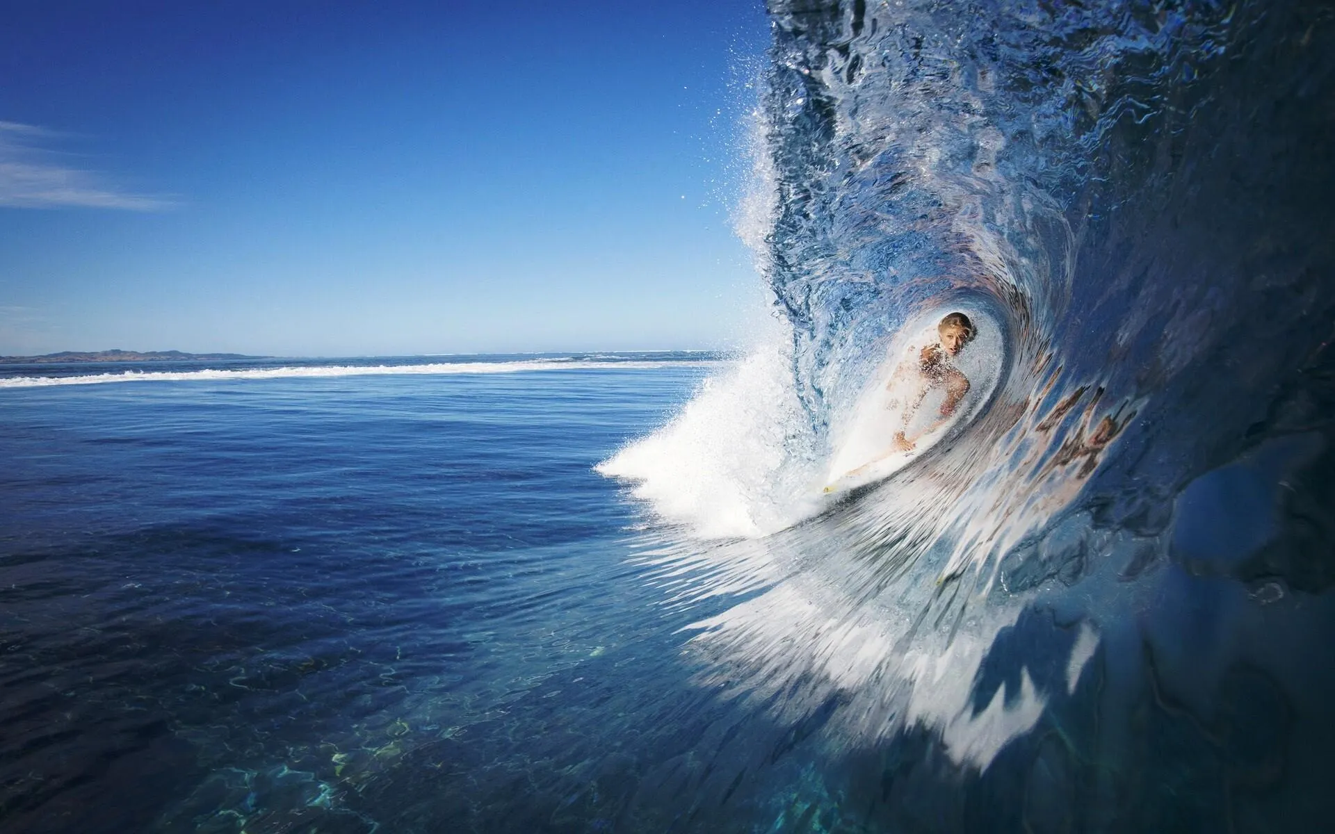 Surfer Riding a Big Wave in the Ocean Under a Blue Sky Image