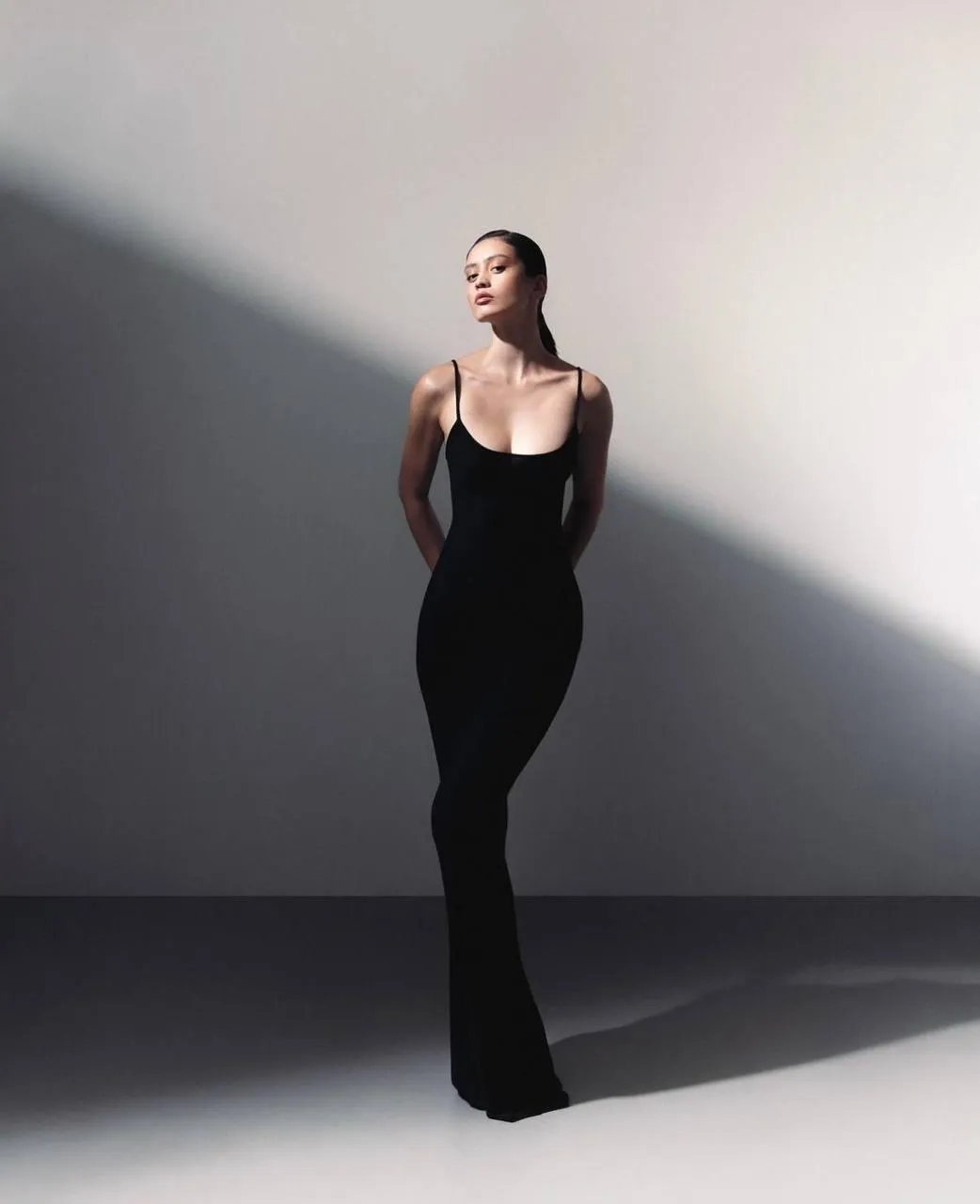 Tall woman standing in a studio wearing a black dress image