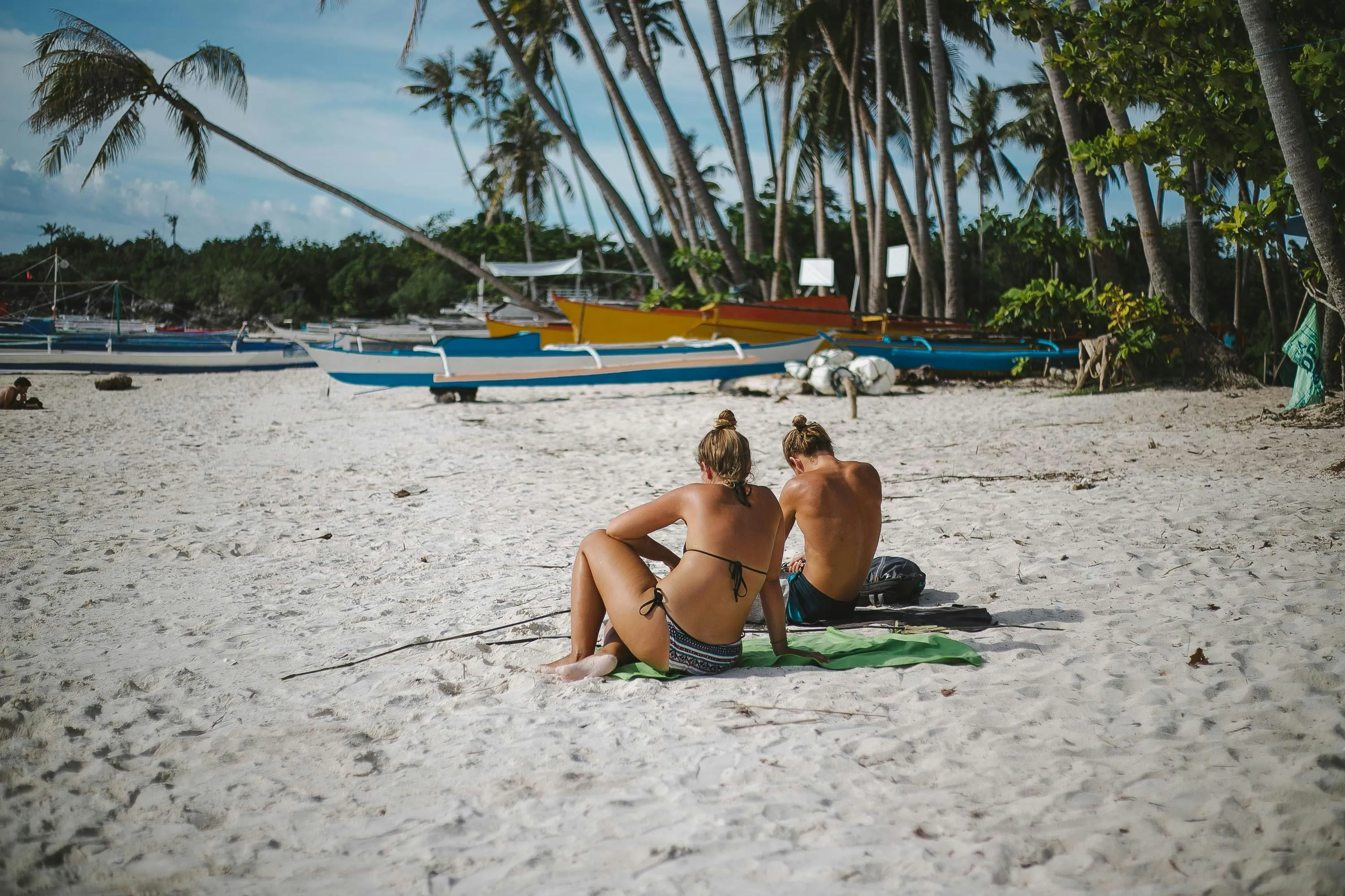 Two Women Lounging on a Tropical Beach Under Palm Trees