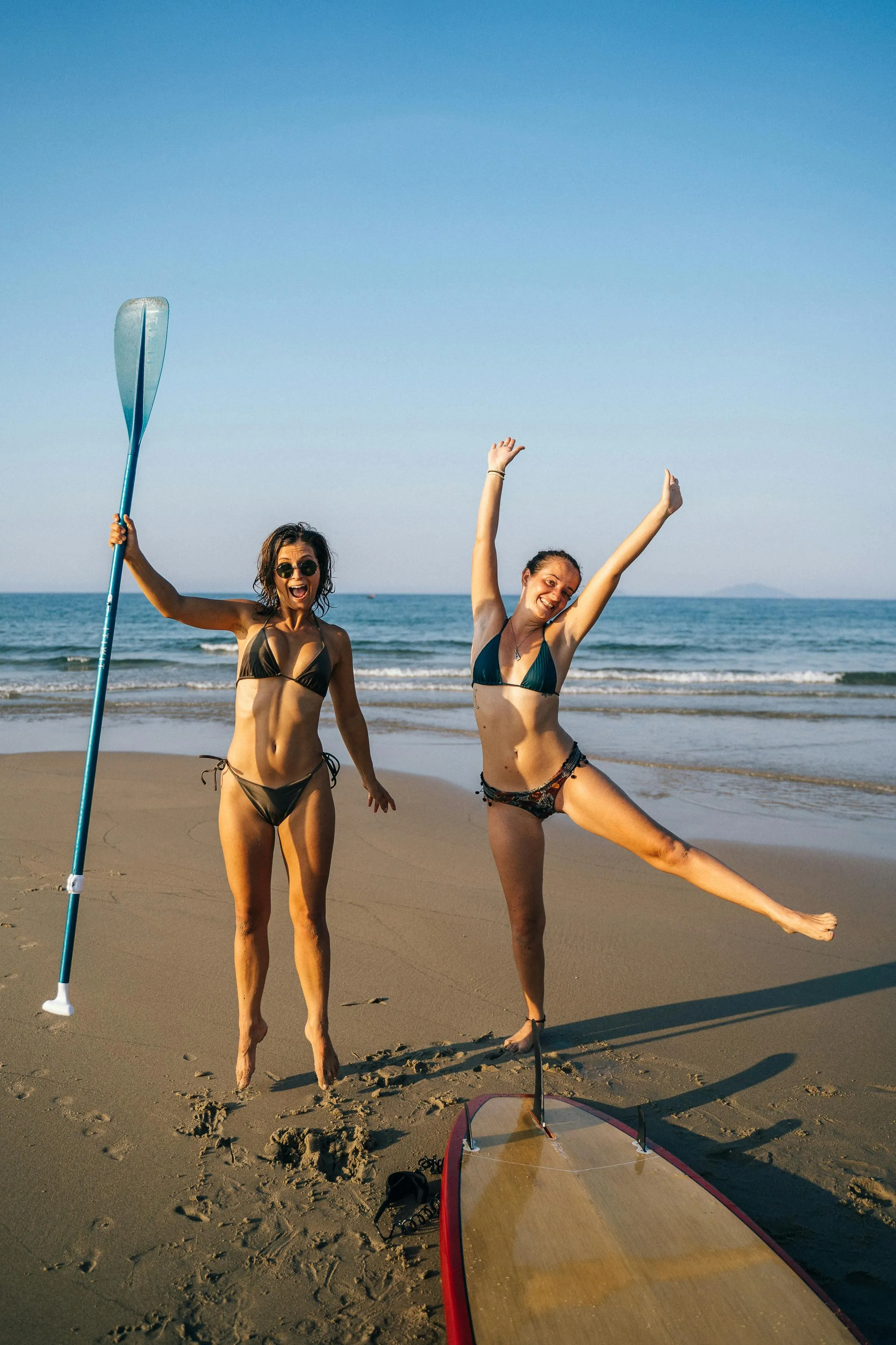Two Women Paddleboarding And Having Fun at the Beach Image