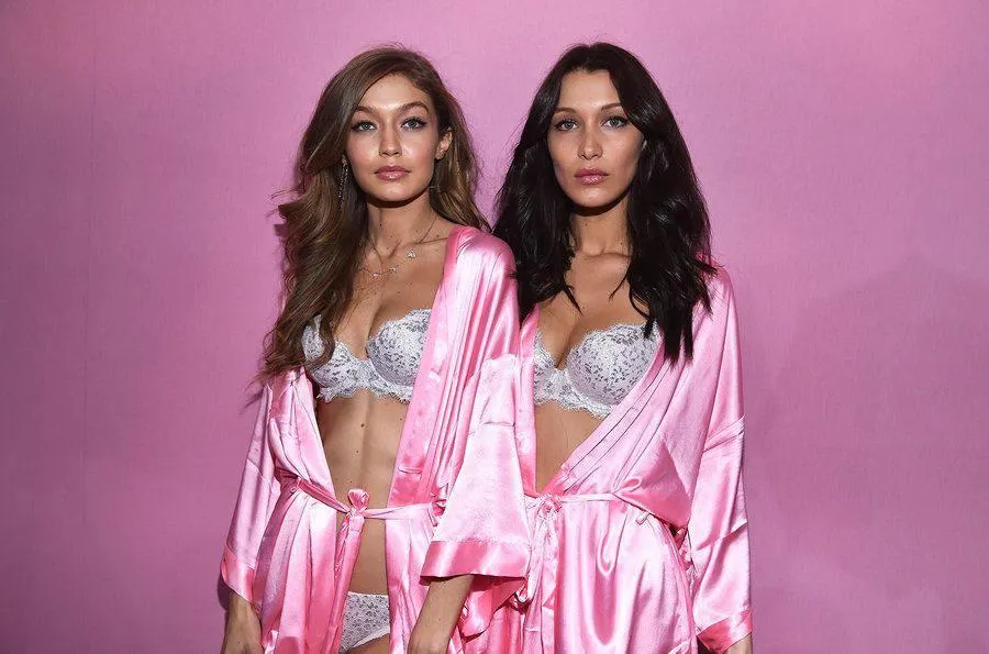Two women wearing matching pink satin robes near a pink wall