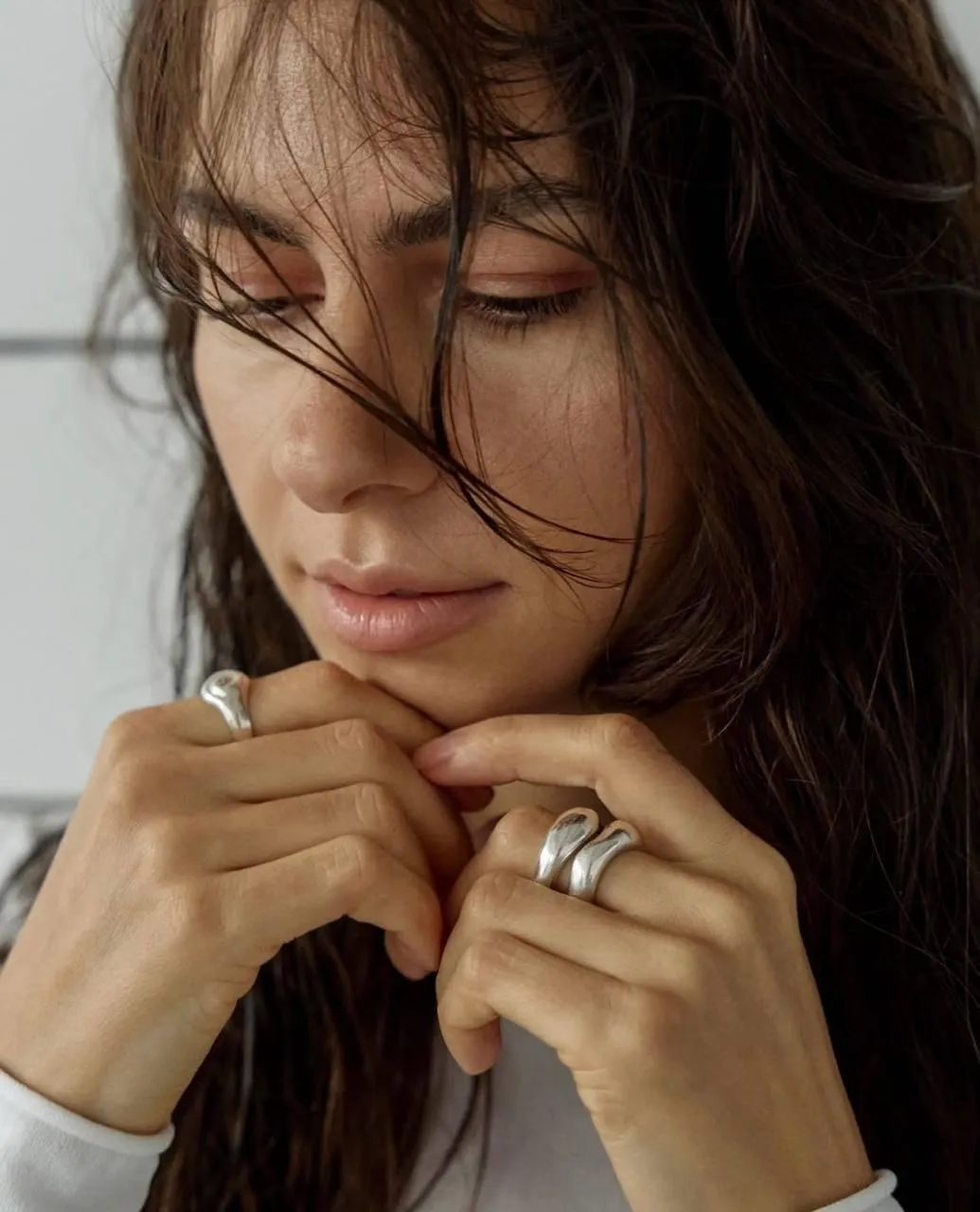 Wet Haired Woman Touches Her Lips While Looking Down Image