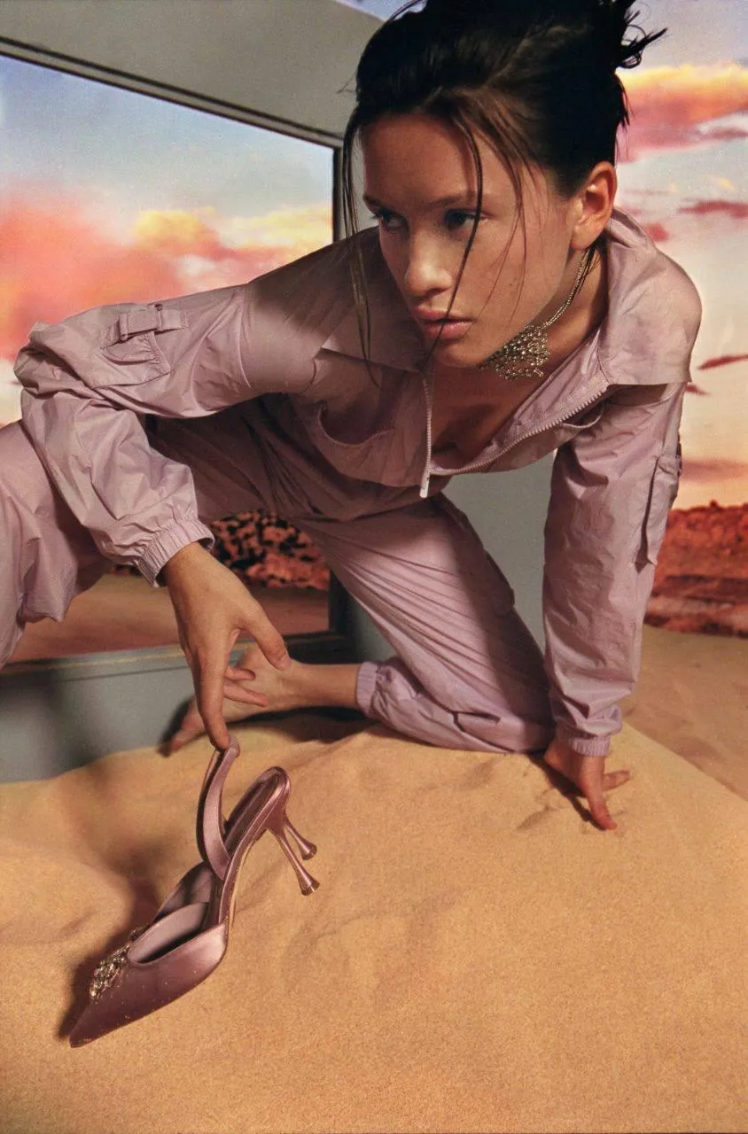 Woman Crouching on Sand in a Sunset with a Moody Style Image