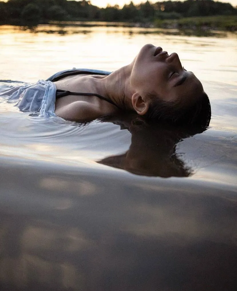 Woman floating peacefully in calm water at sunset Wallpaper
