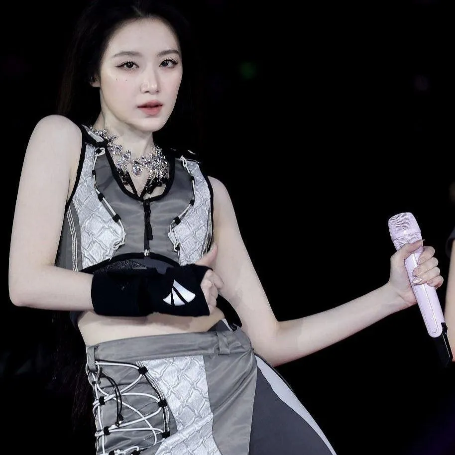 Woman holding a mic performing on stage with gloves on hand