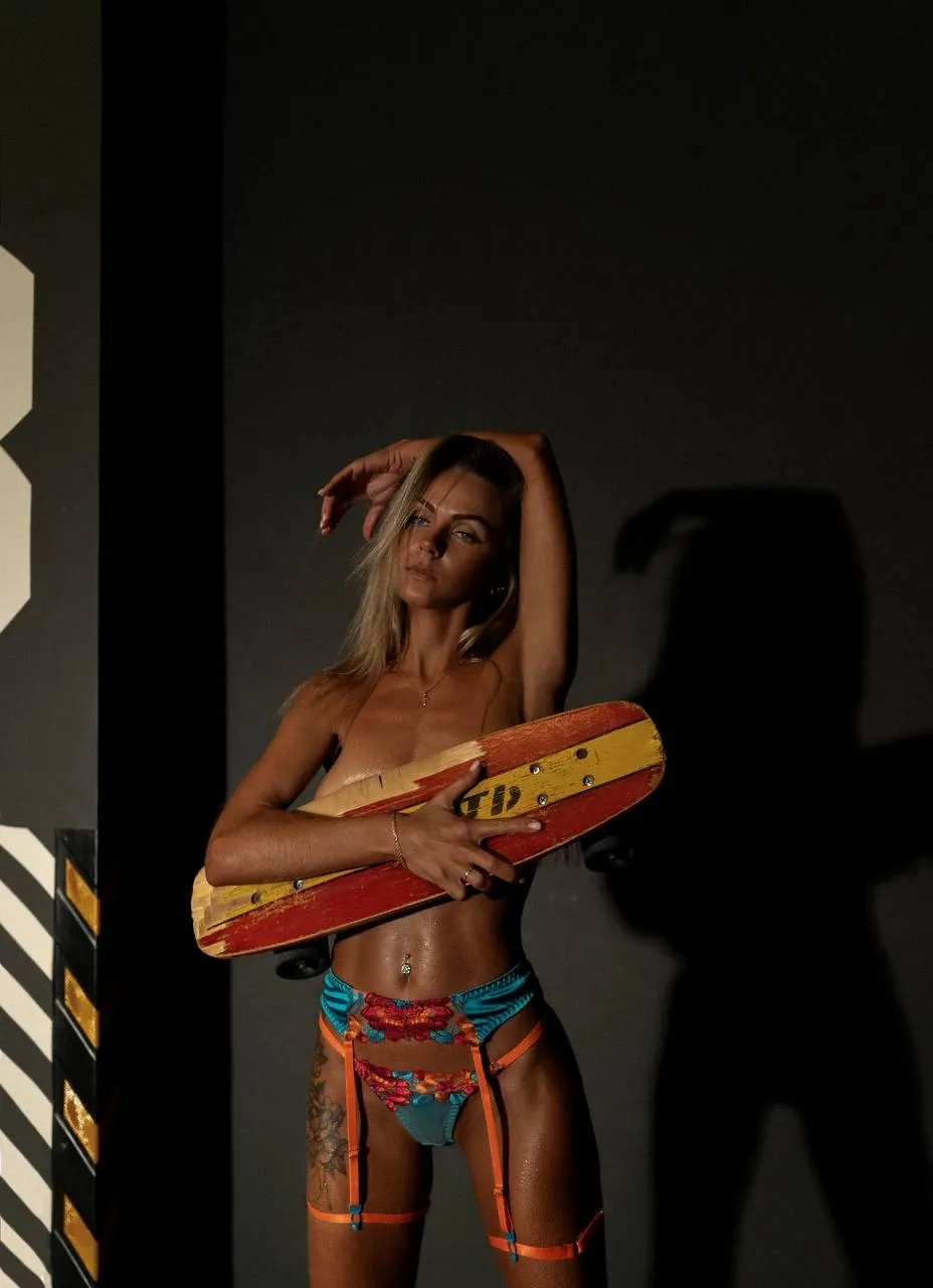 Woman holding a skateboard in a dramatic shadow lighting