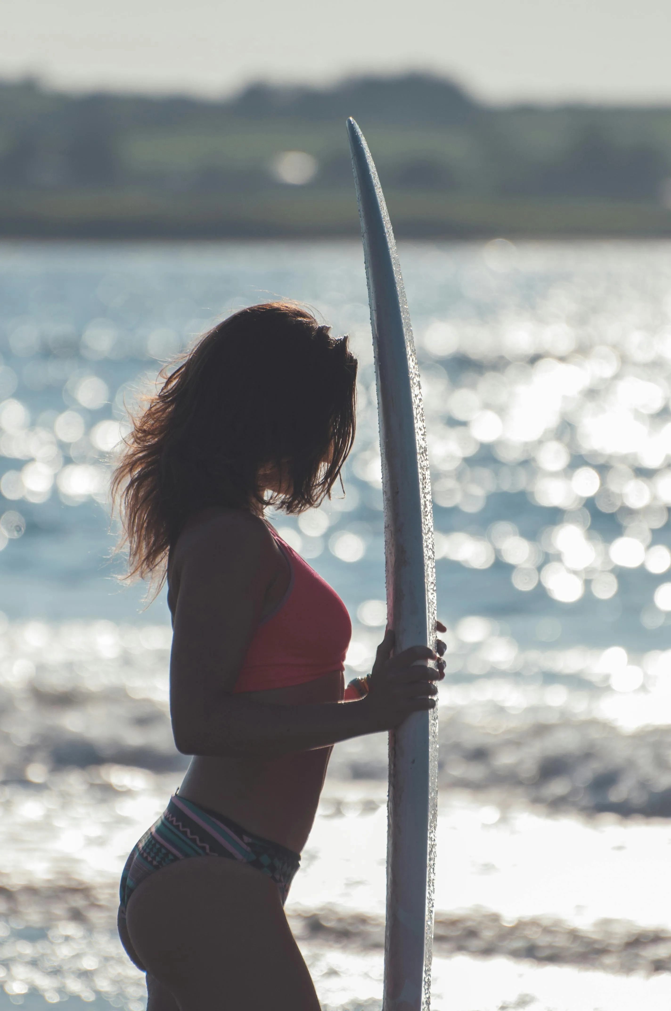 Woman Holding a Surfboard Looking Out at the Ocean Wallpaper