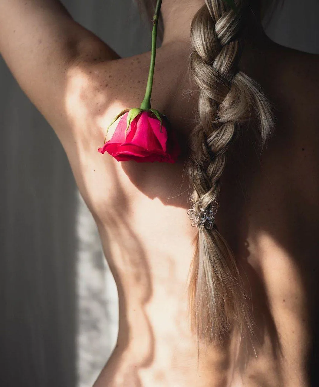 Woman Holding Pink Rose Behind Her Back with Her Braid Down
