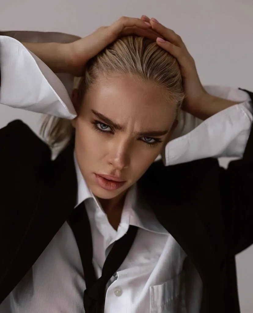 Woman in a black and white outfit hand on her head wallpaper