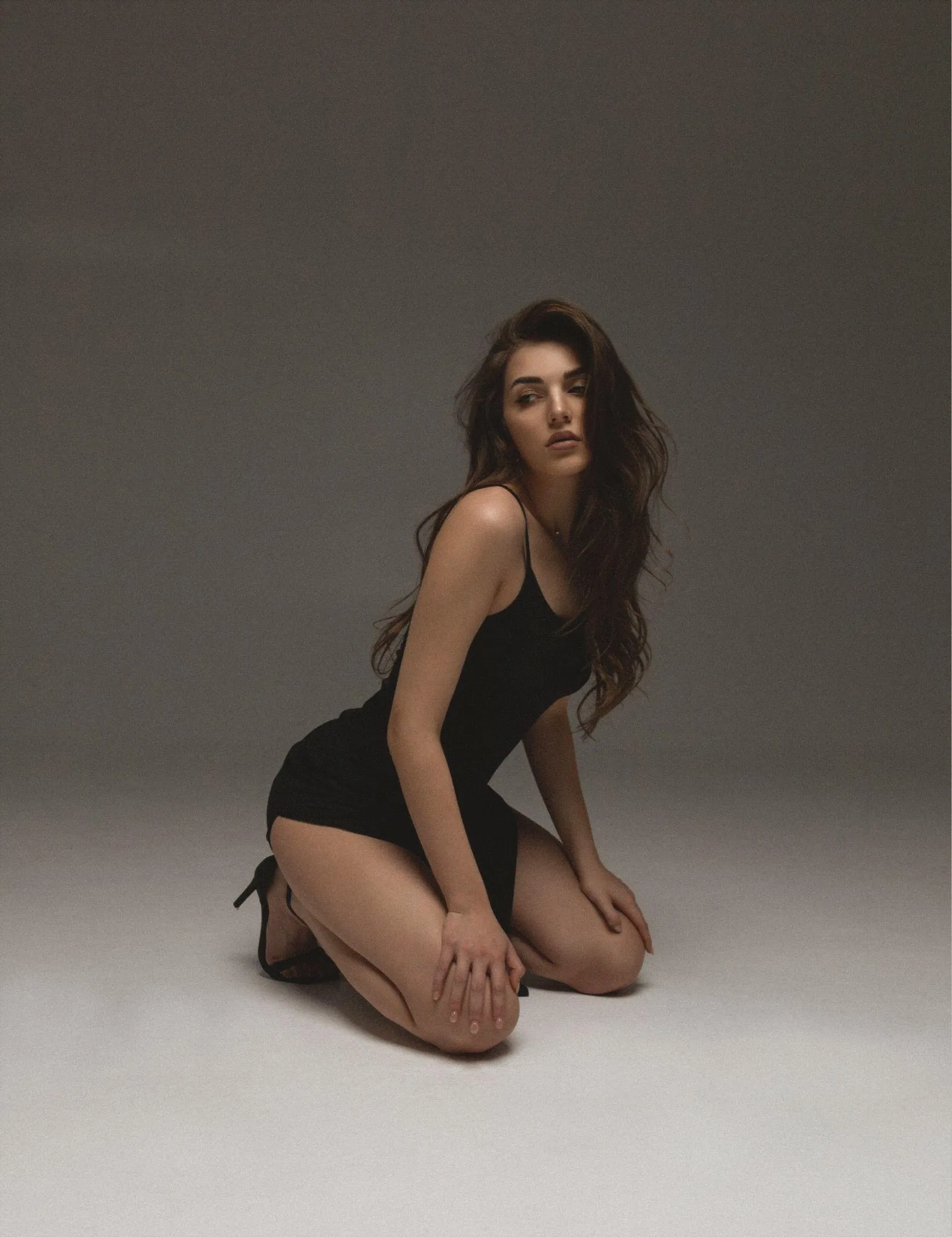 Woman in a Black Bodysuit Kneeling in Soft Natural Lighting
