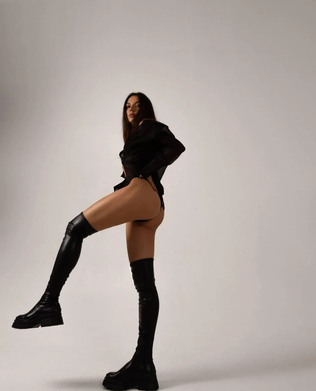 Woman in a black dress standing on one leg on the floor