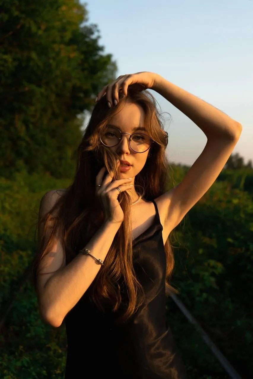 Woman in a black dress touching her hair under golden light