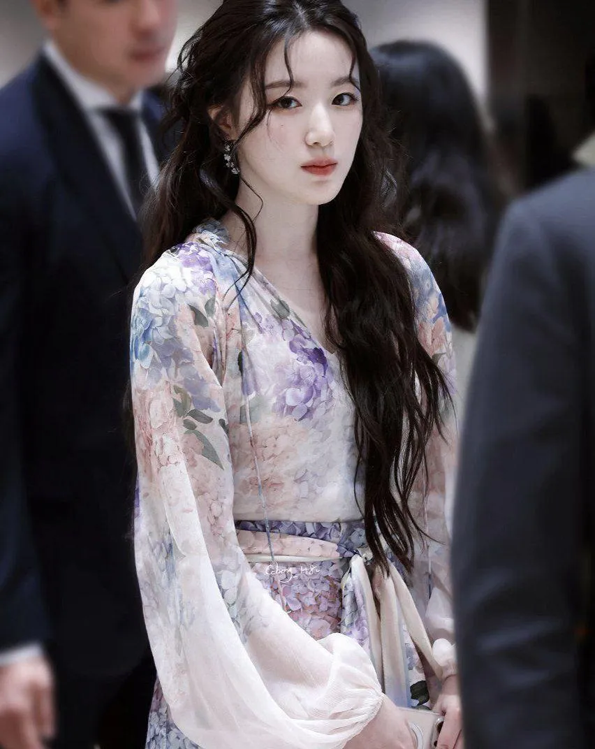 Woman in a Floral Sheer Dress Walking Through Crowded Event