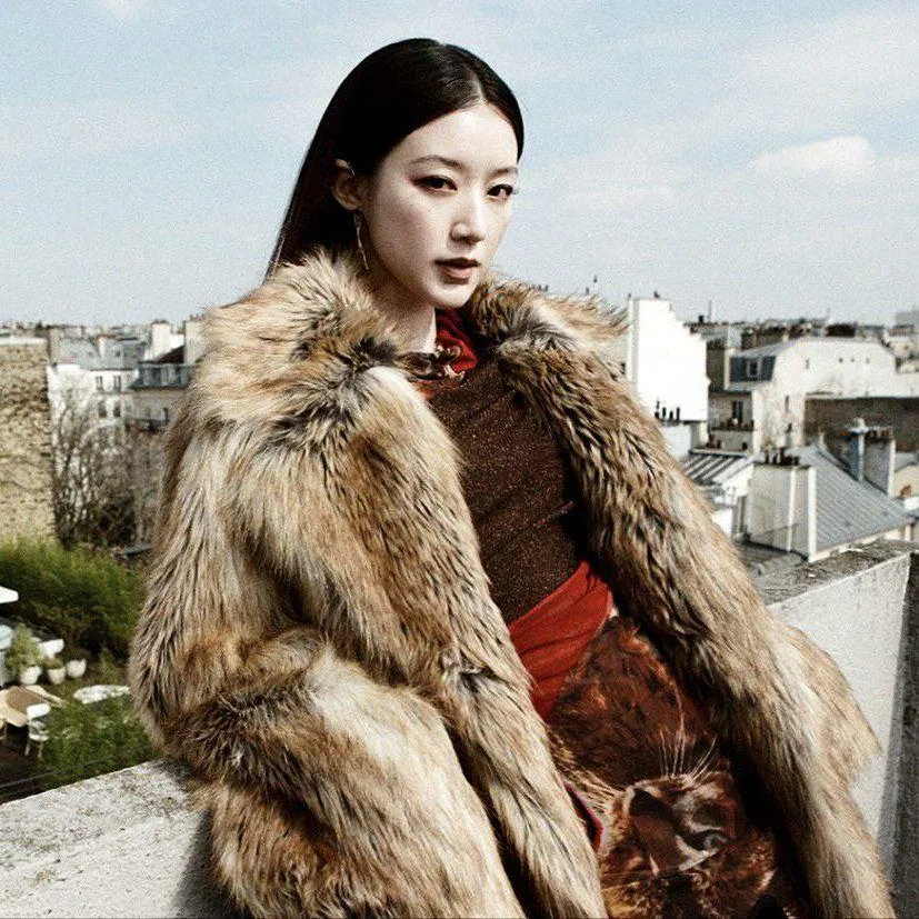Woman in a Fur Coat Posing on Rooftop with City Skyline View
