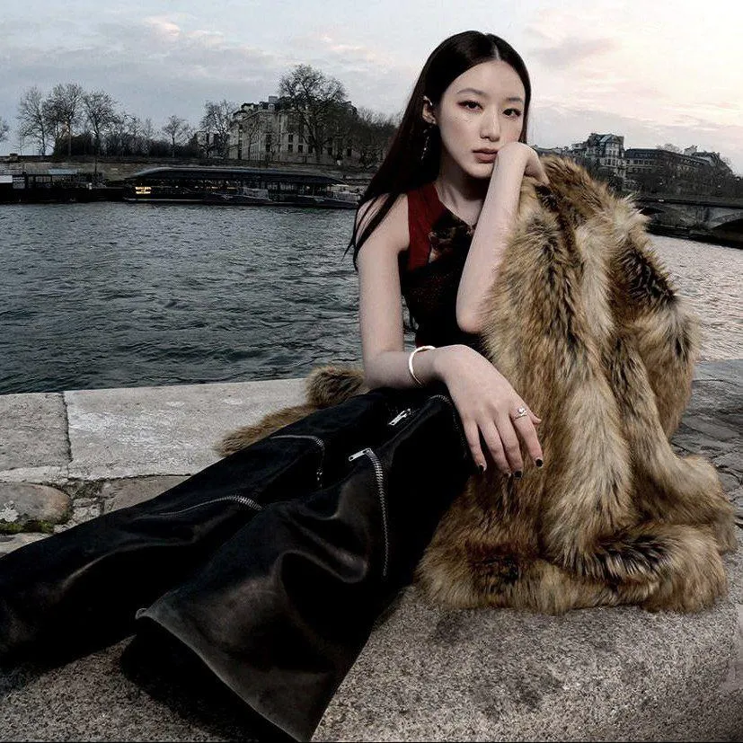 Woman in a Fur Coat Sitting Outdoors by River with Soft Gaze