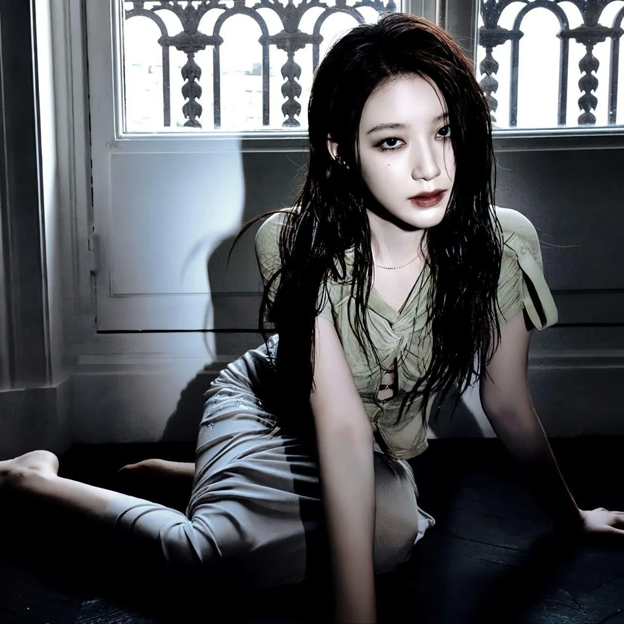 Woman in a Green Top Sitting on the Floor Near the Window