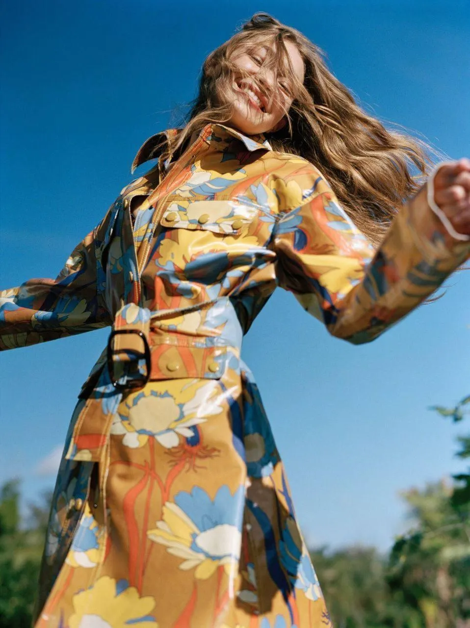 Woman in a Patterned Coat Smiling Under a Bright Outdoor Sky