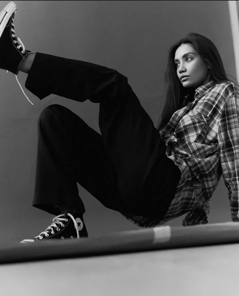Woman in a plaid shirt posing on edge with one foot raised