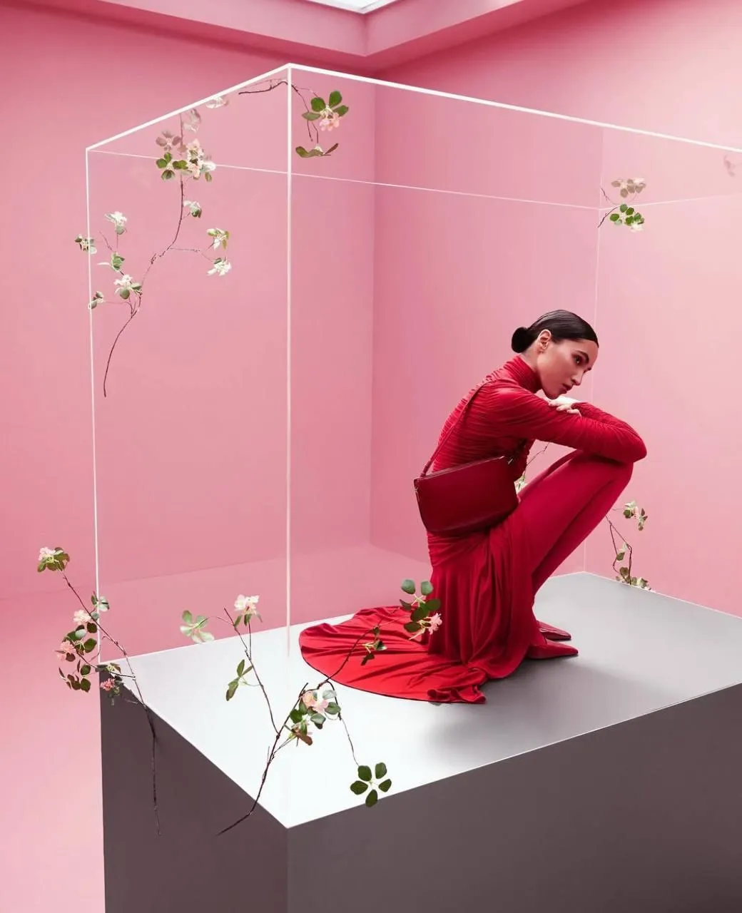 Woman in a red dress crouching in a pink floral display box
