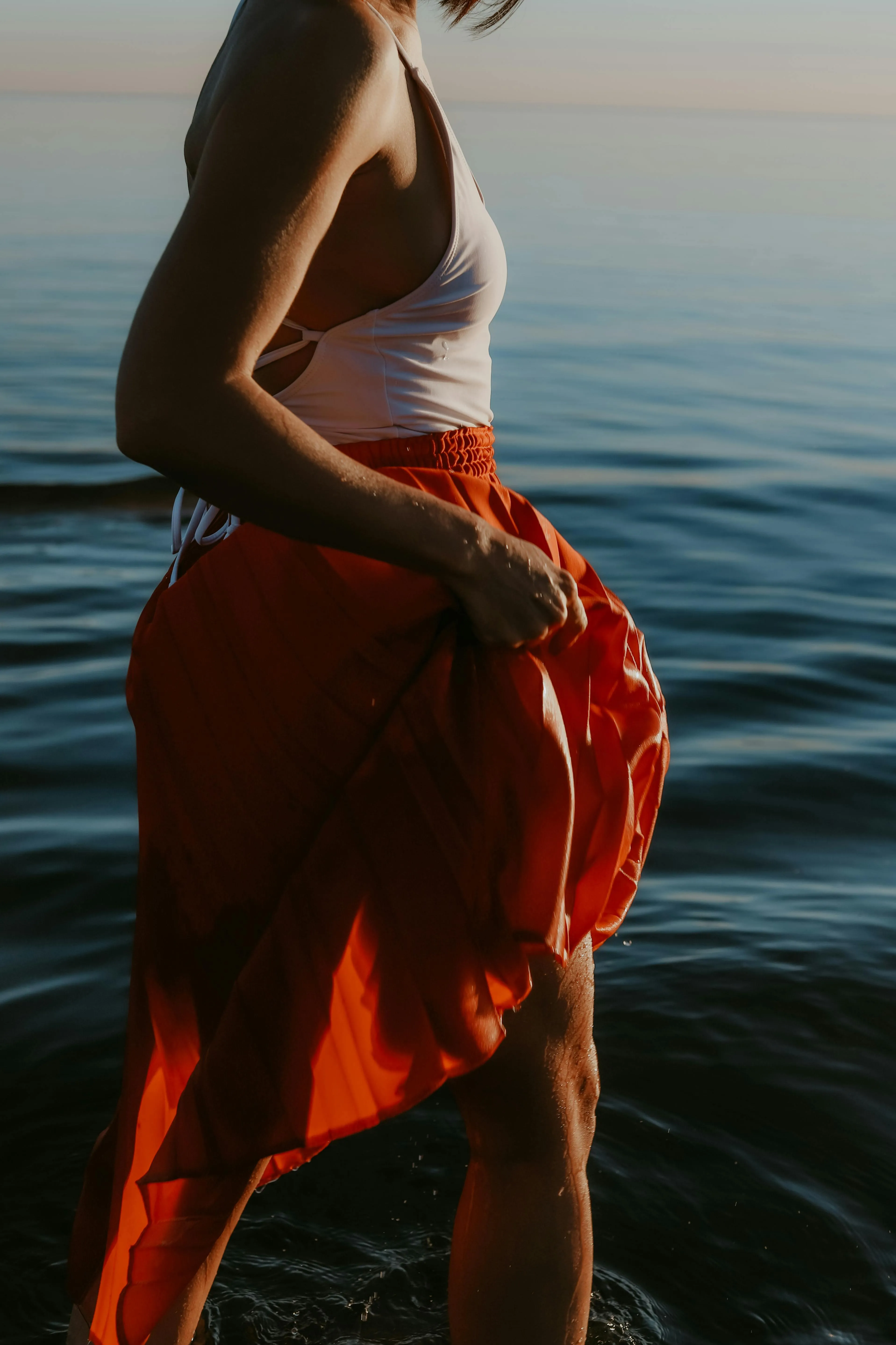 Woman in a Red Skirt Standing by Calm Reflective Seawater