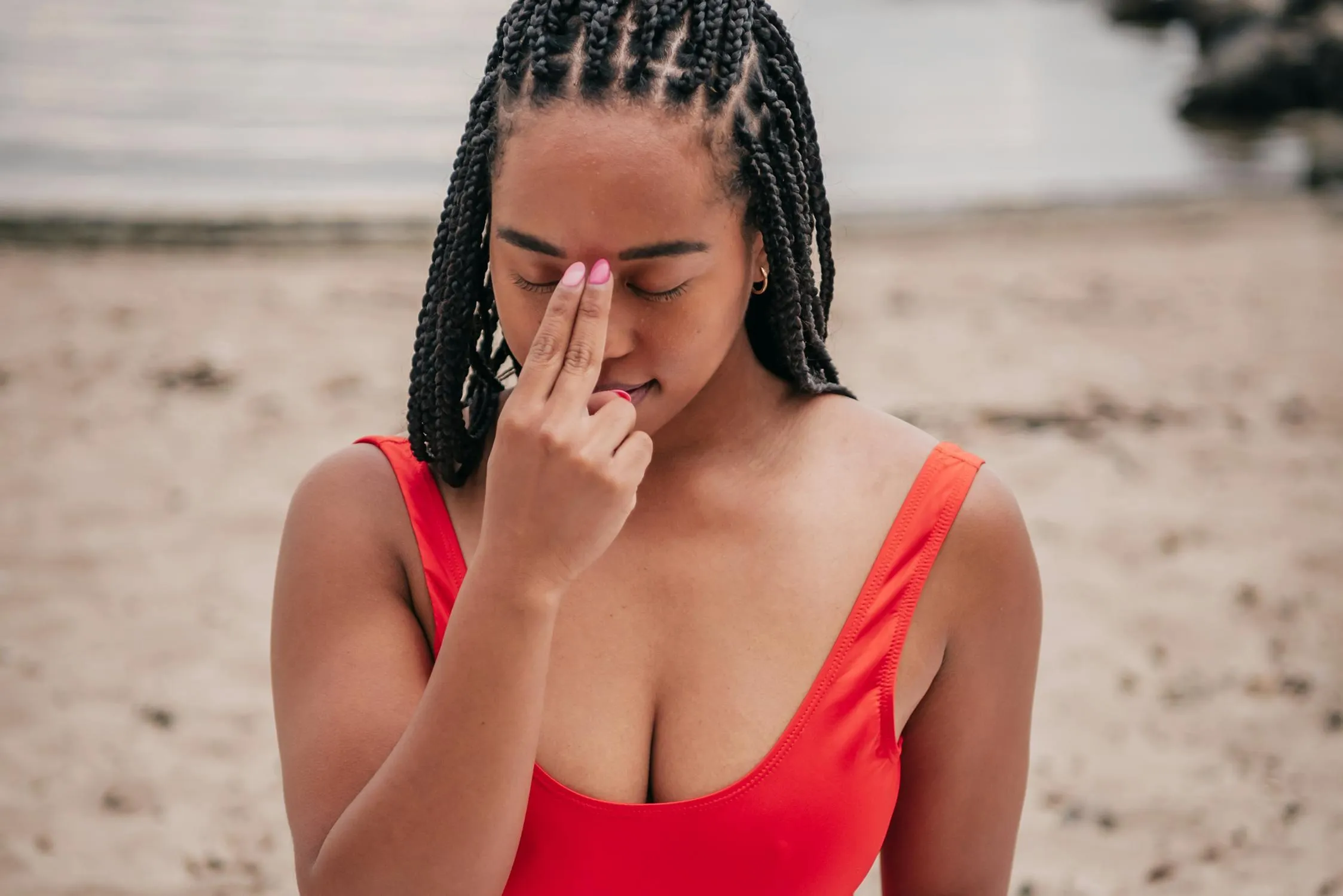 Woman in a Red Top on the Beach Wipes Water From Her Face