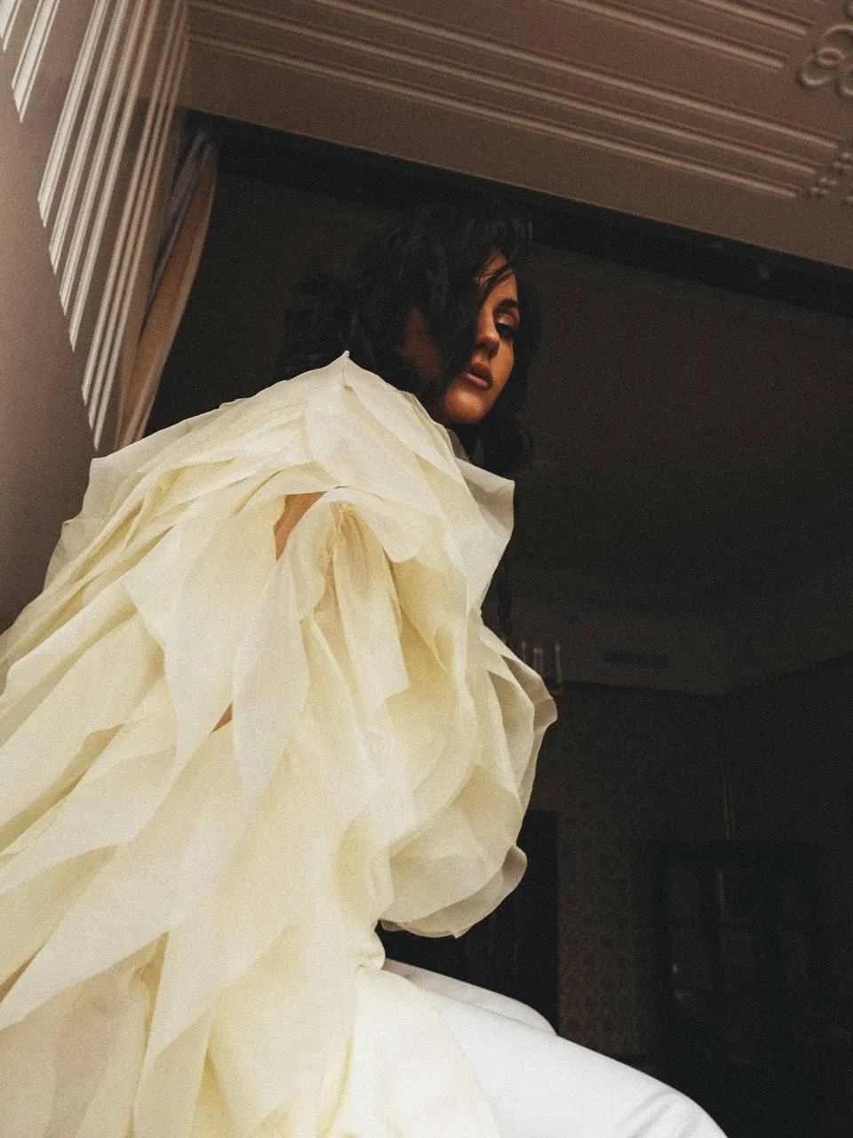 Woman in a Ruffled Dress Walking Down a Stairway Indoors