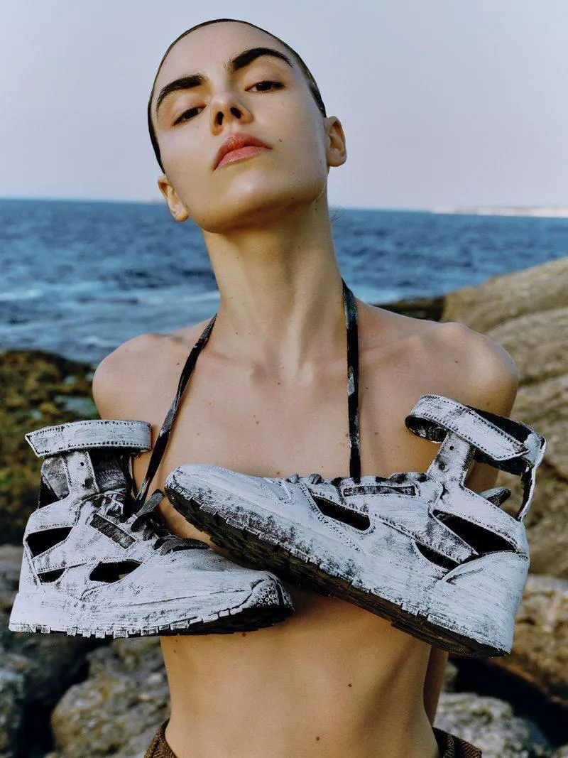 Woman in a Sculptural Top Standing by the Seashore Wallpaper