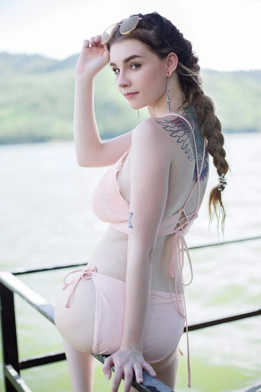 Woman in a sheer pink top posing outdoors near a lake image