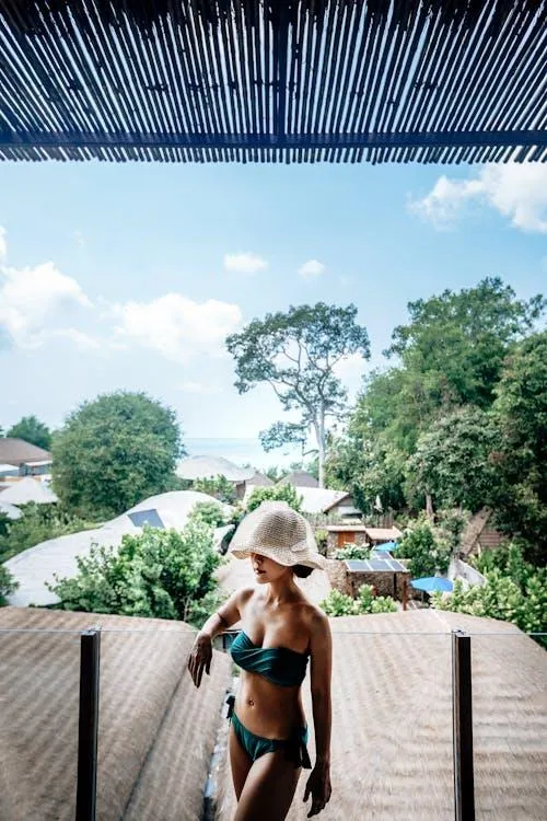 Woman in a swimsuit standing on a balcony under a blue sky