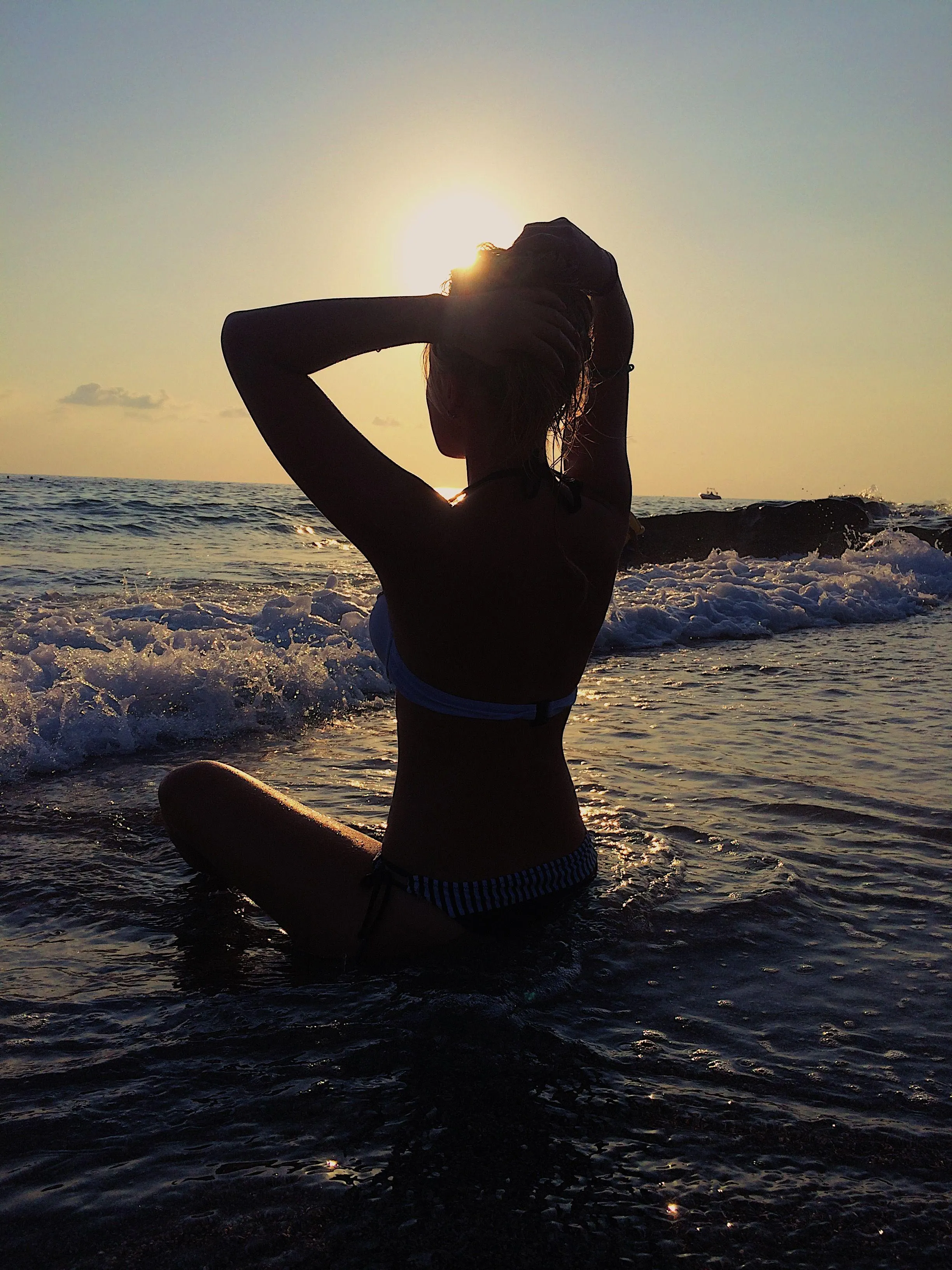 Woman in a Water Silhouette at Sunset with Her Hand Raised