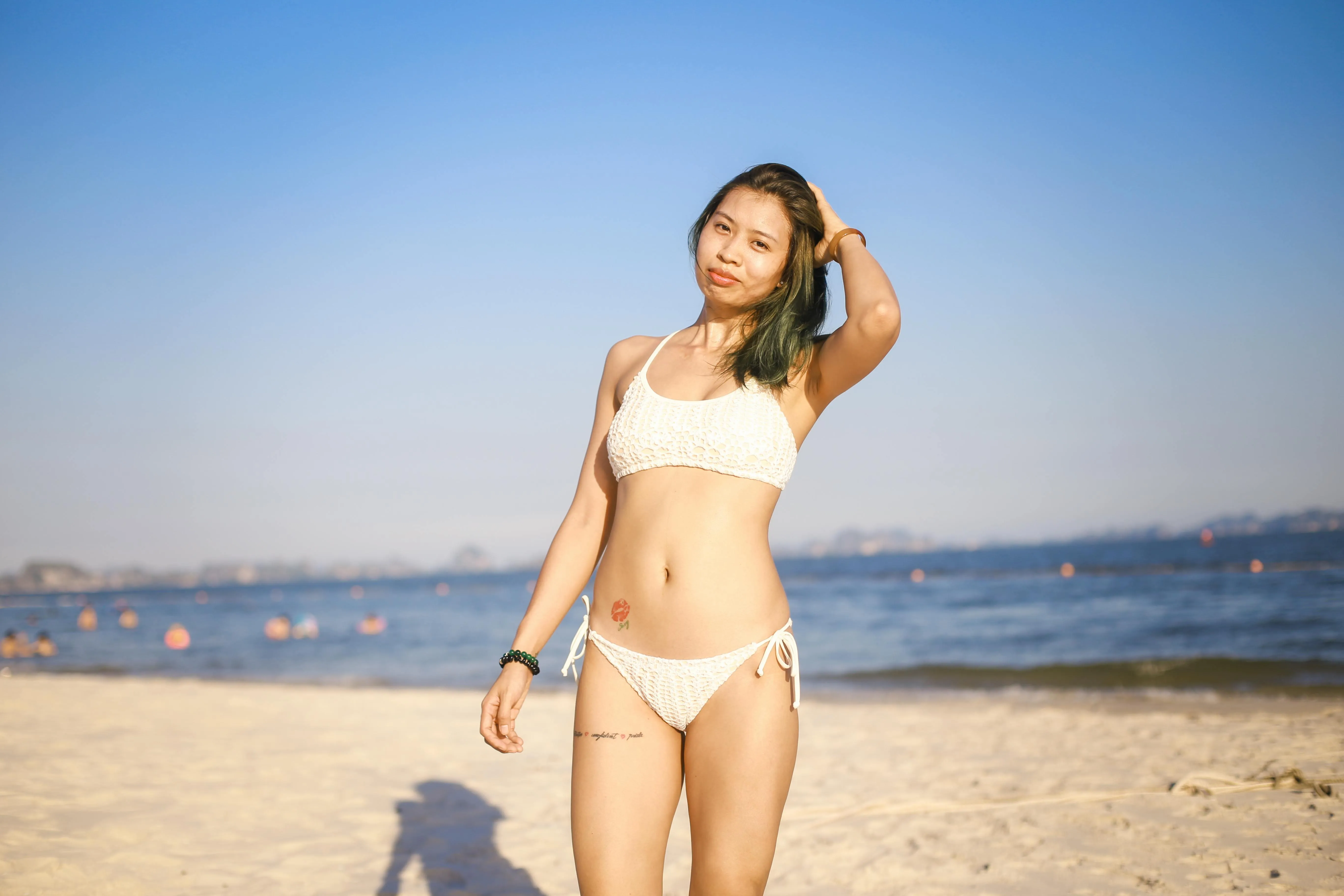 Woman in a White Bikini Standing Confidently on Beach Sand