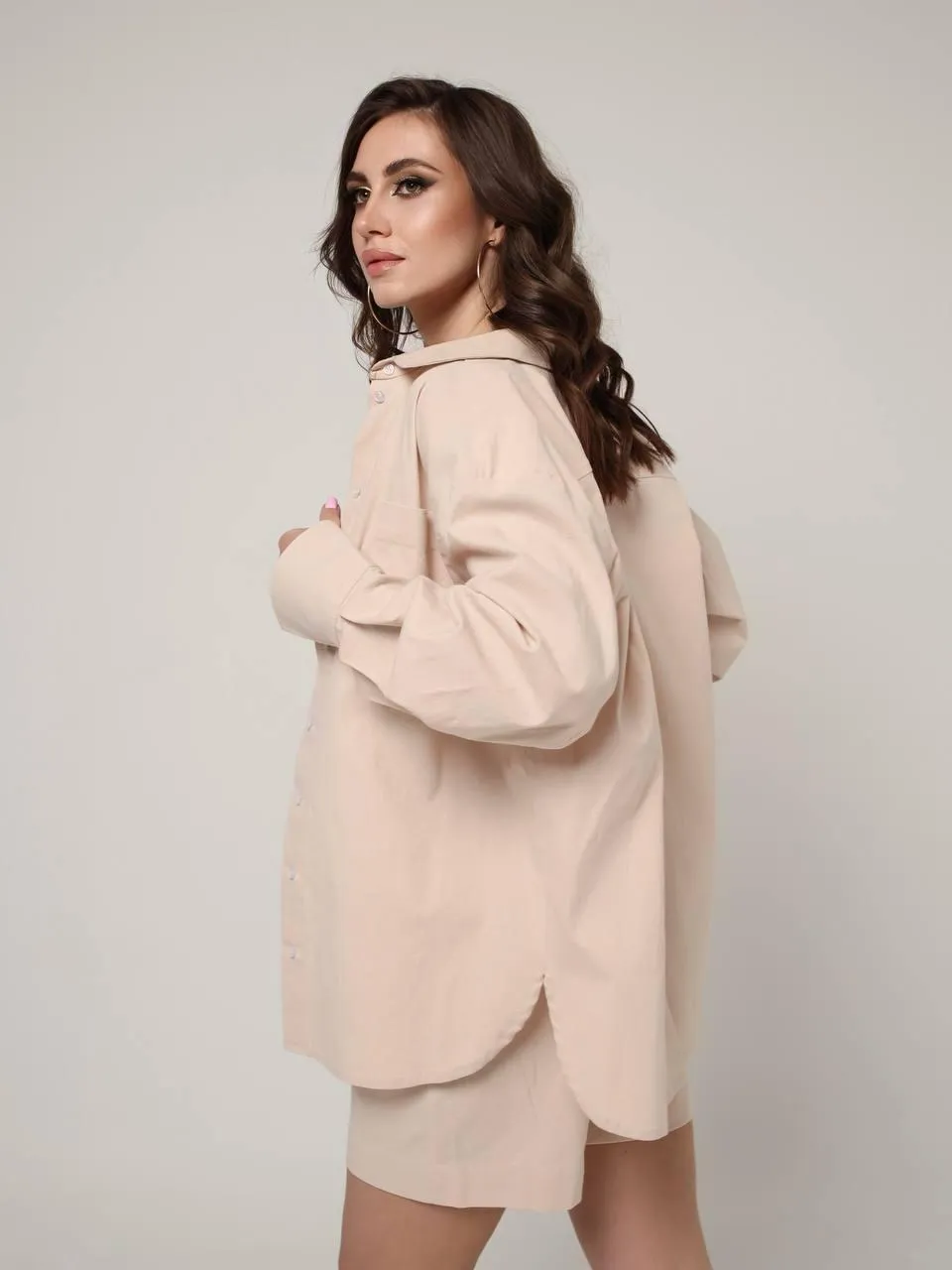 woman in a white coat standing near the studio wall image