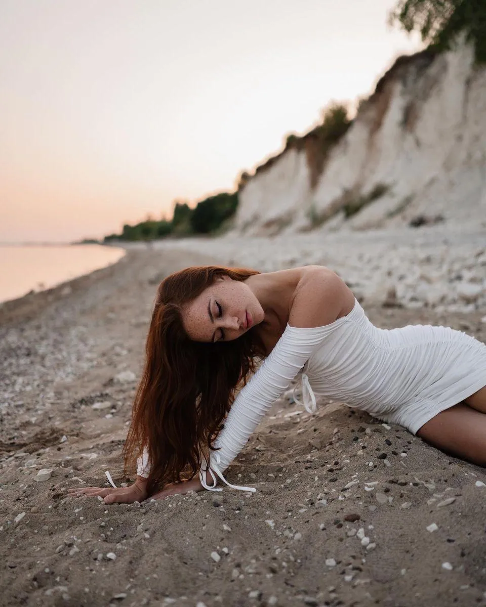 Woman in a White Dress Posing by Cliffs on the Beach Image