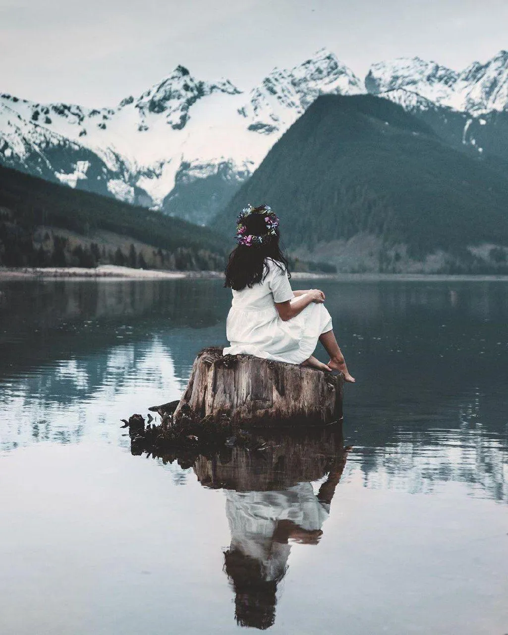 Woman in a White Dress Sitting on a Rock by a Mountain Lake