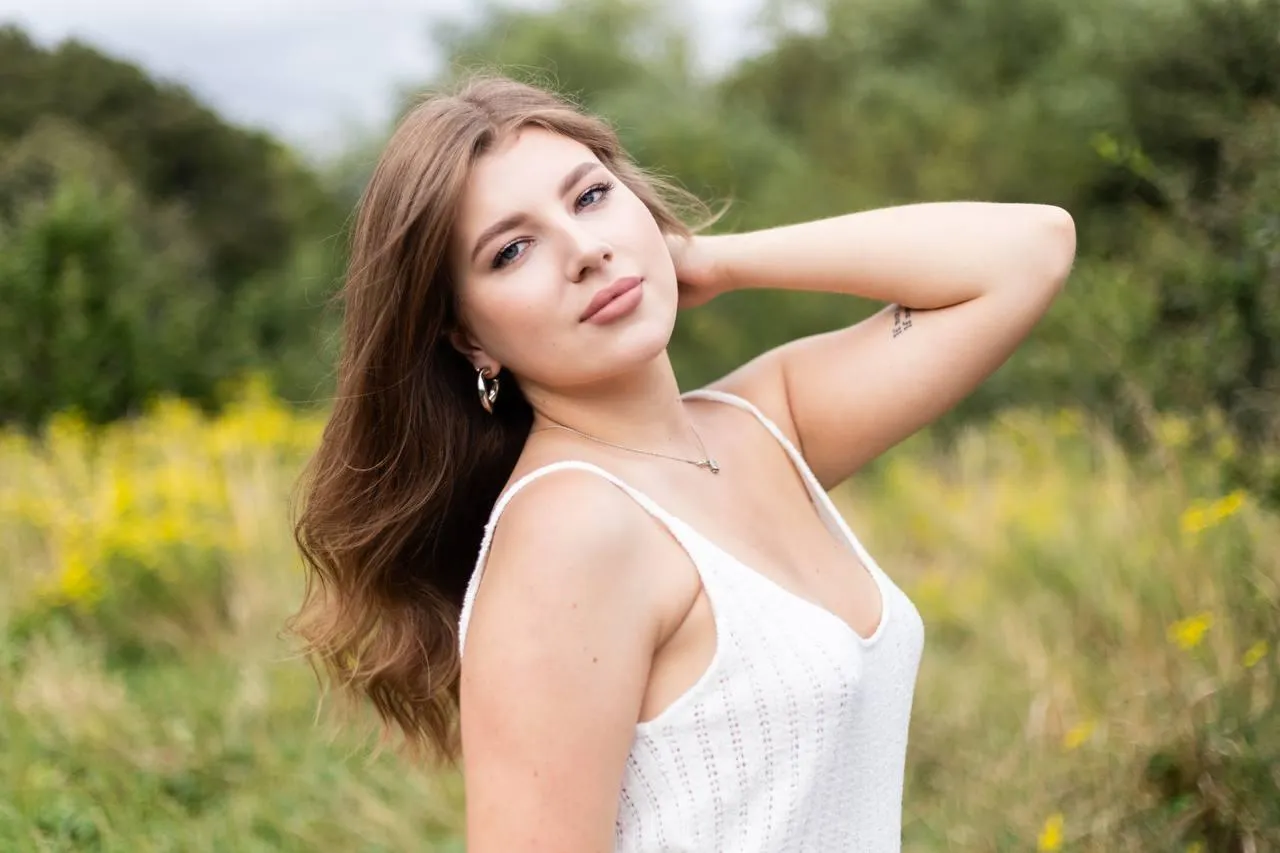 Woman in a white dress smiles while touching her hair image