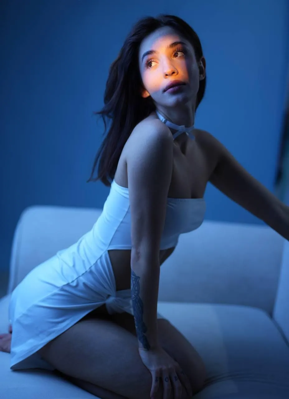 Woman in a white dress with a tattoo in soft blue lighting