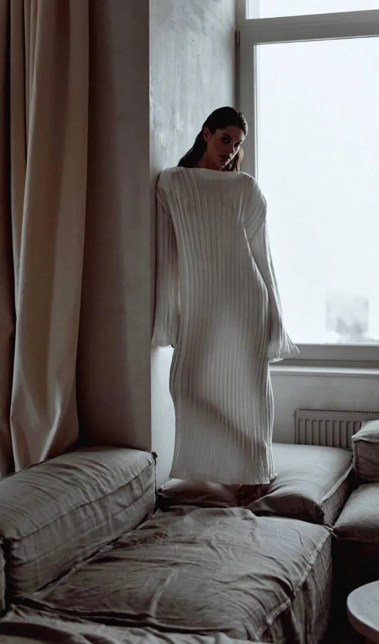 Woman in a white knit dress walking across the bedroom image