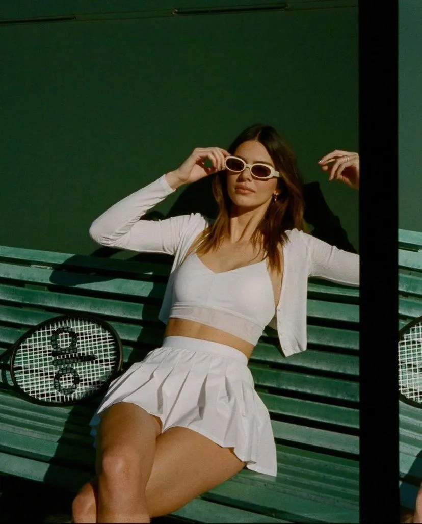 Woman in a white outfit lounging with a graffiti background