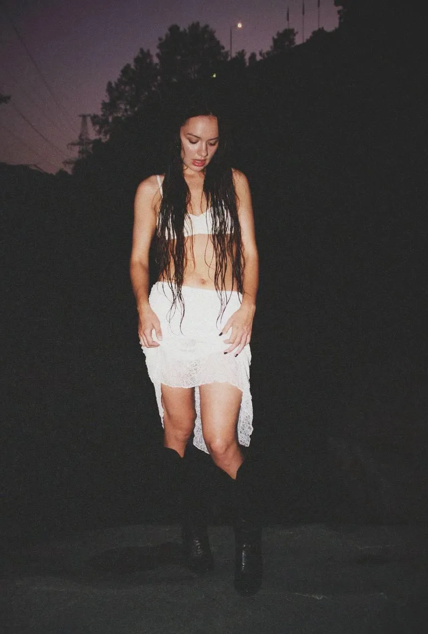 Woman in a White Outfit Standing Outdoors in the Low Light