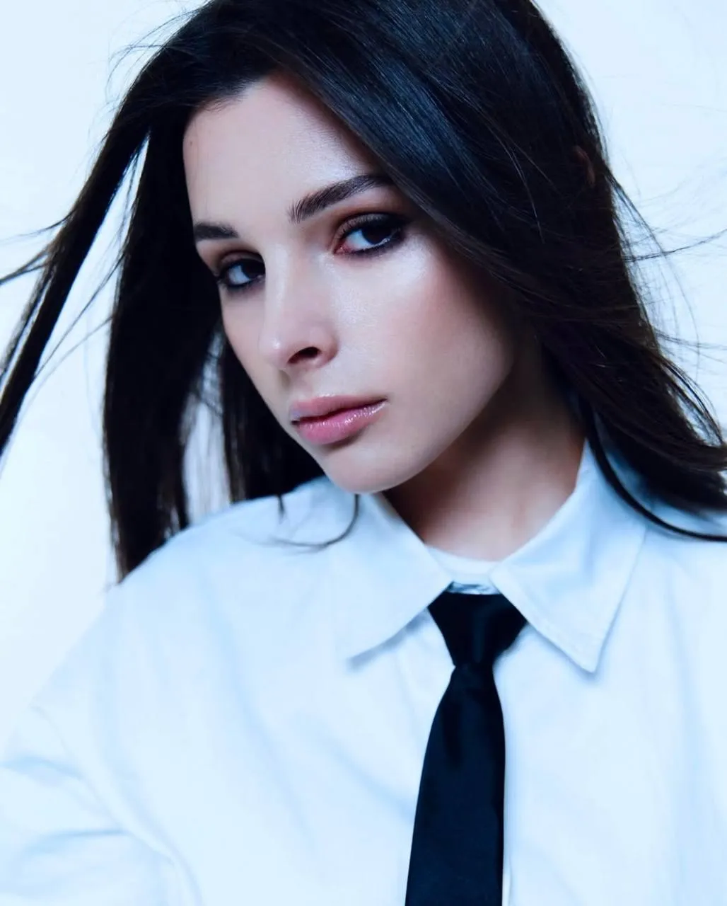 Woman in a white shirt and tie posing with a confident gaze
