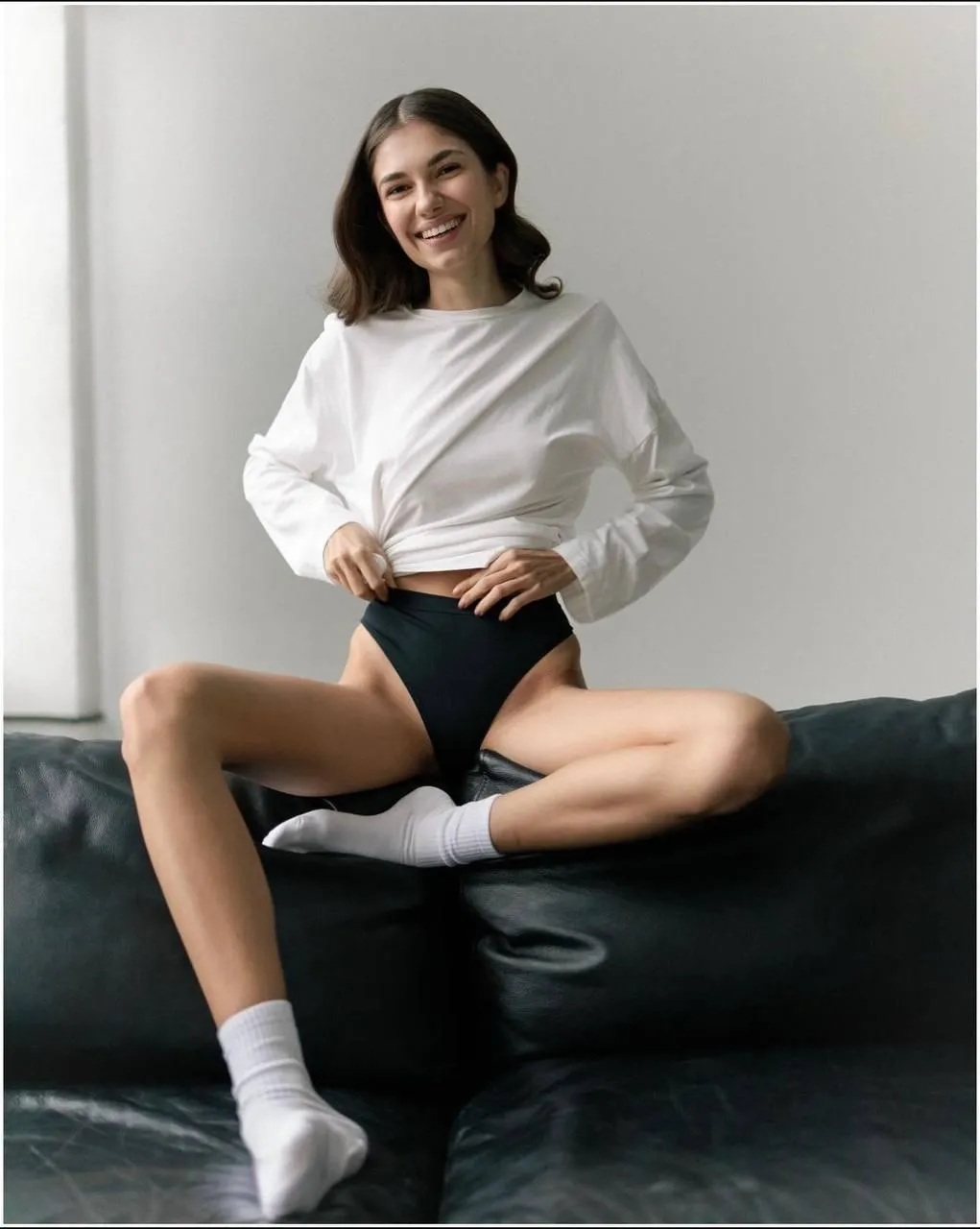 Woman in a white shirt posing casually on a bright bed image