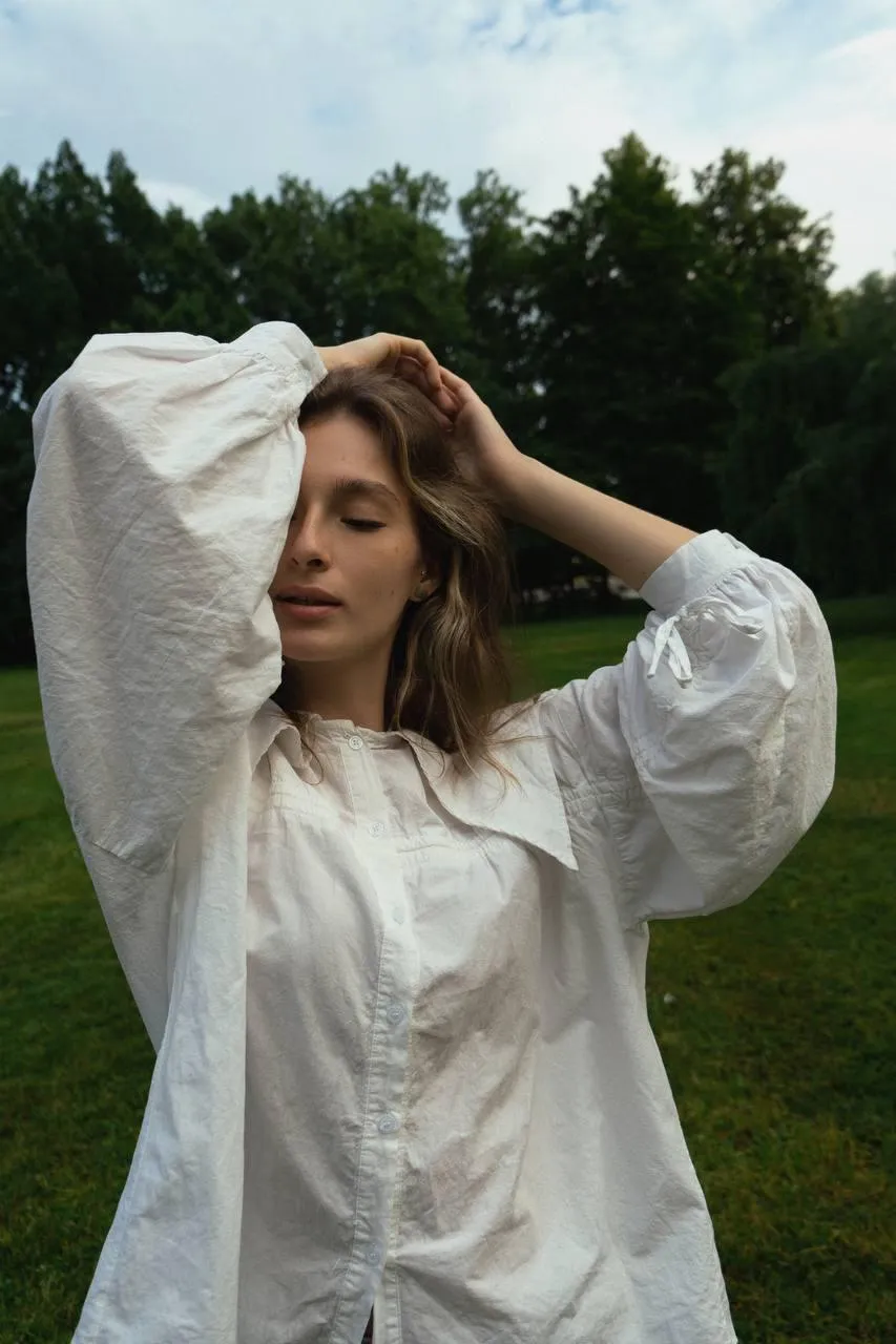 Woman in a White Shirt Standing in a Green Open Field Image