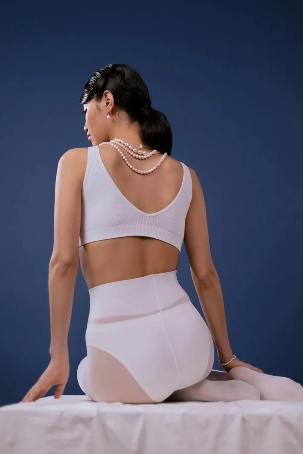 Woman in a white skirt posing elegantly on a soft surface