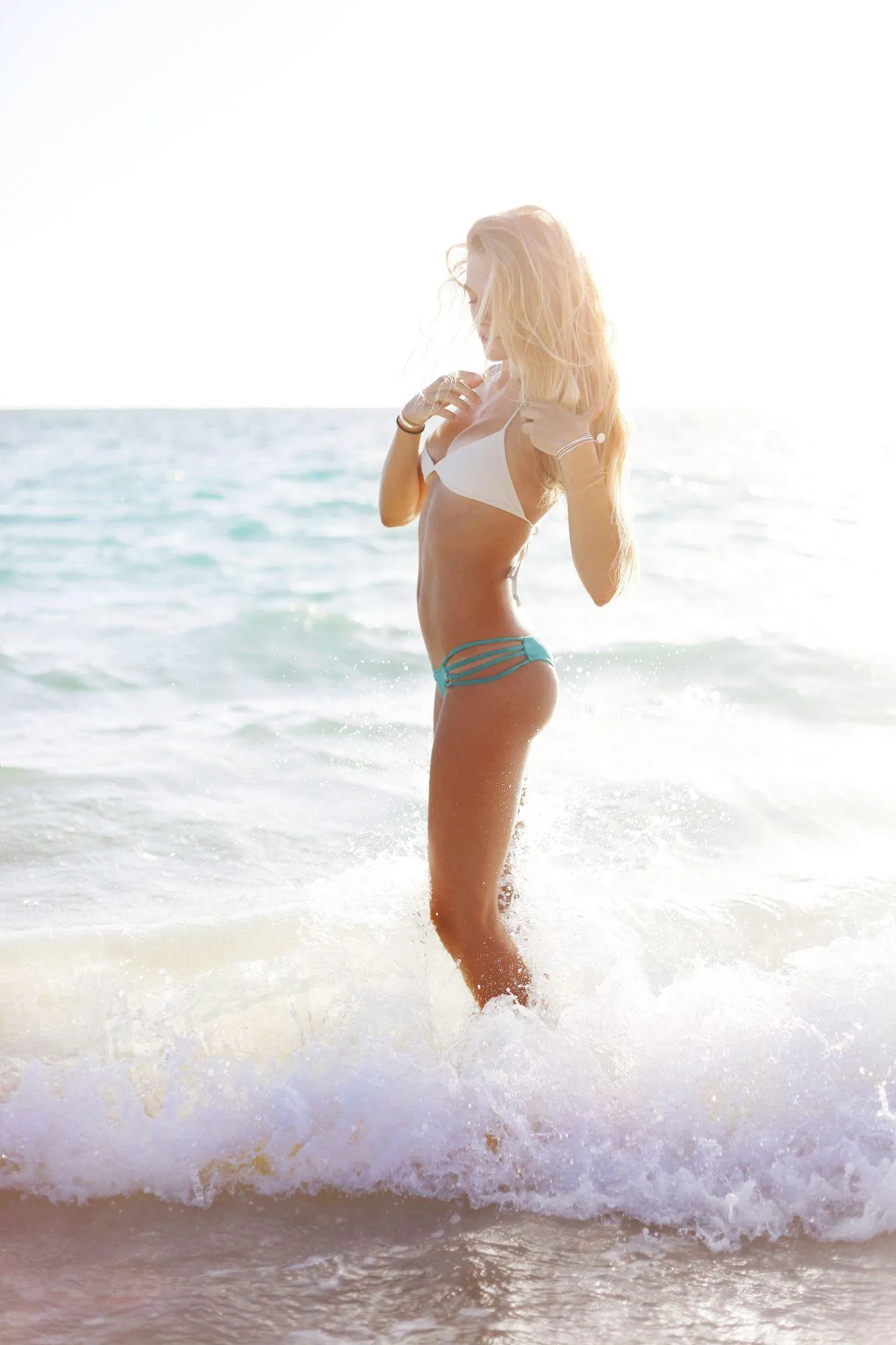 Woman in a White Swimsuit Standing in a Shallow Ocean Tide