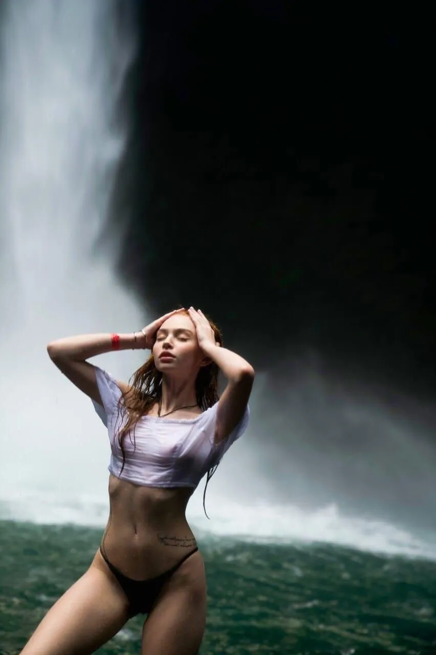 Woman in a white top and black underwear near the waterfall