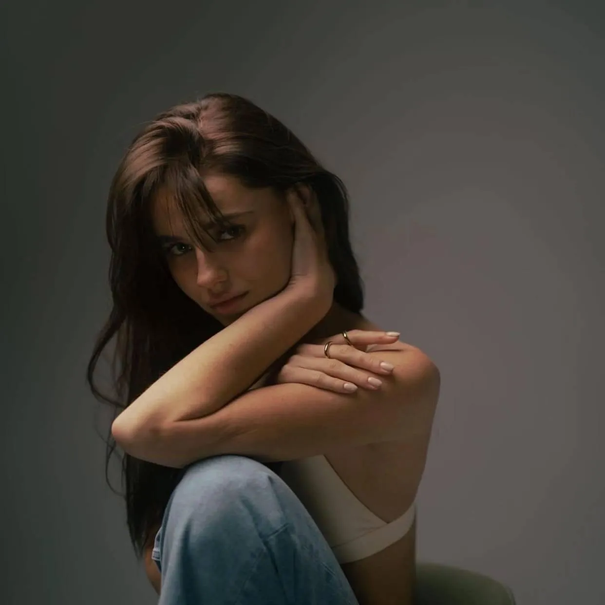 woman in a white top and blue jeans hand on her cheek image