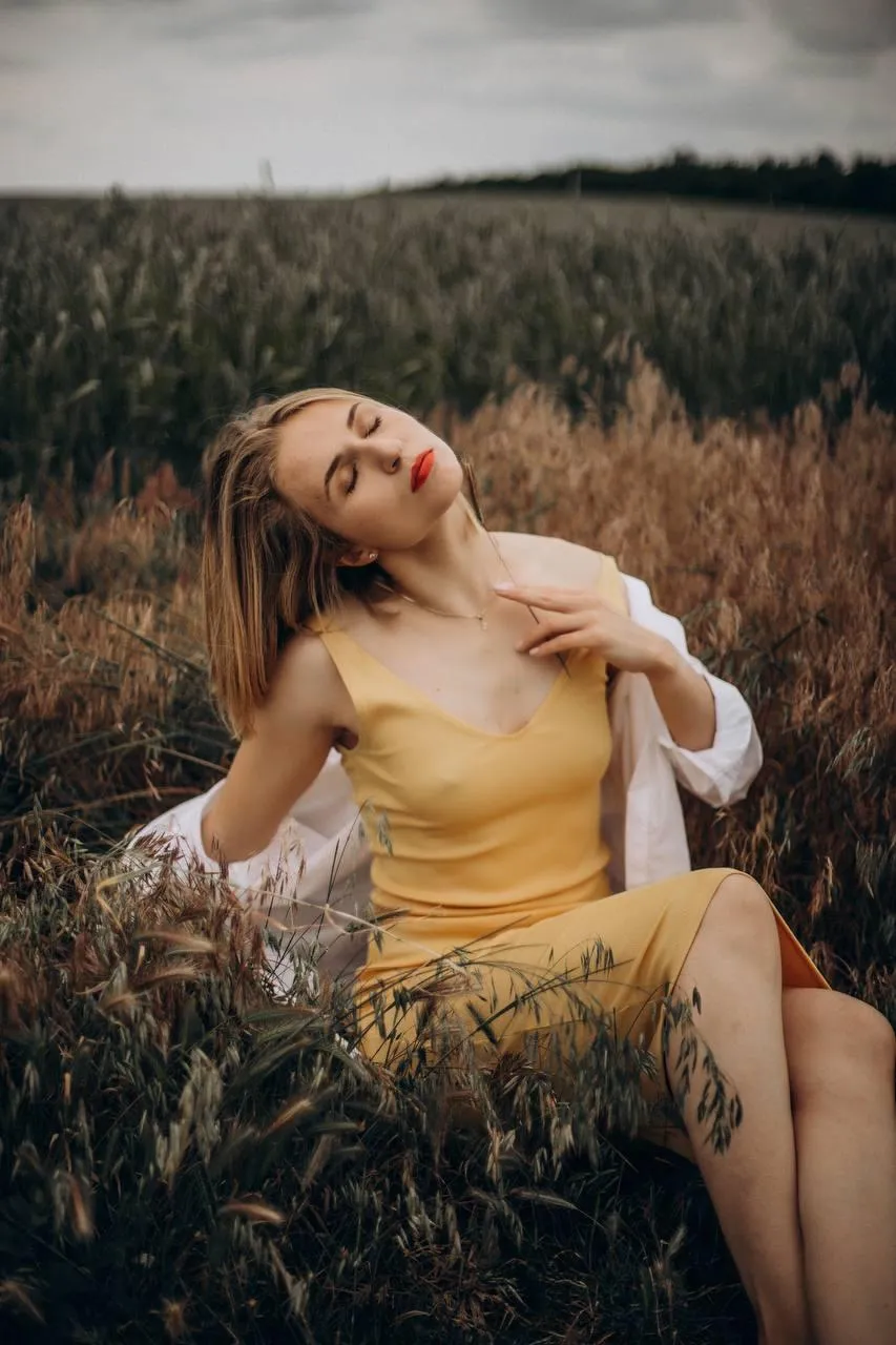 Woman in a Yellow Dress Sitting in a Golden Wheat Field